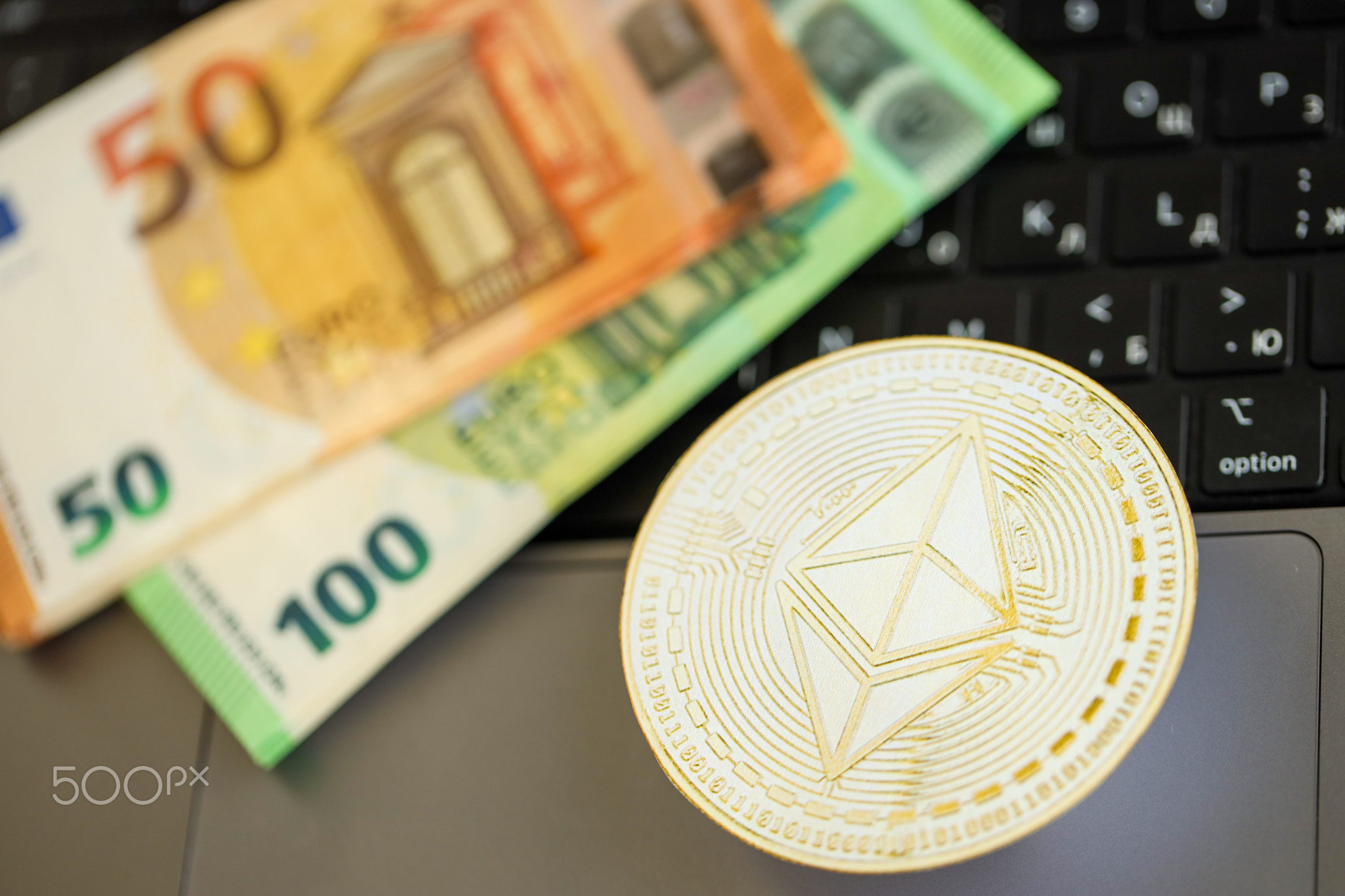 Ethereum ETH coin with big amount of european euro bills on laptop surface