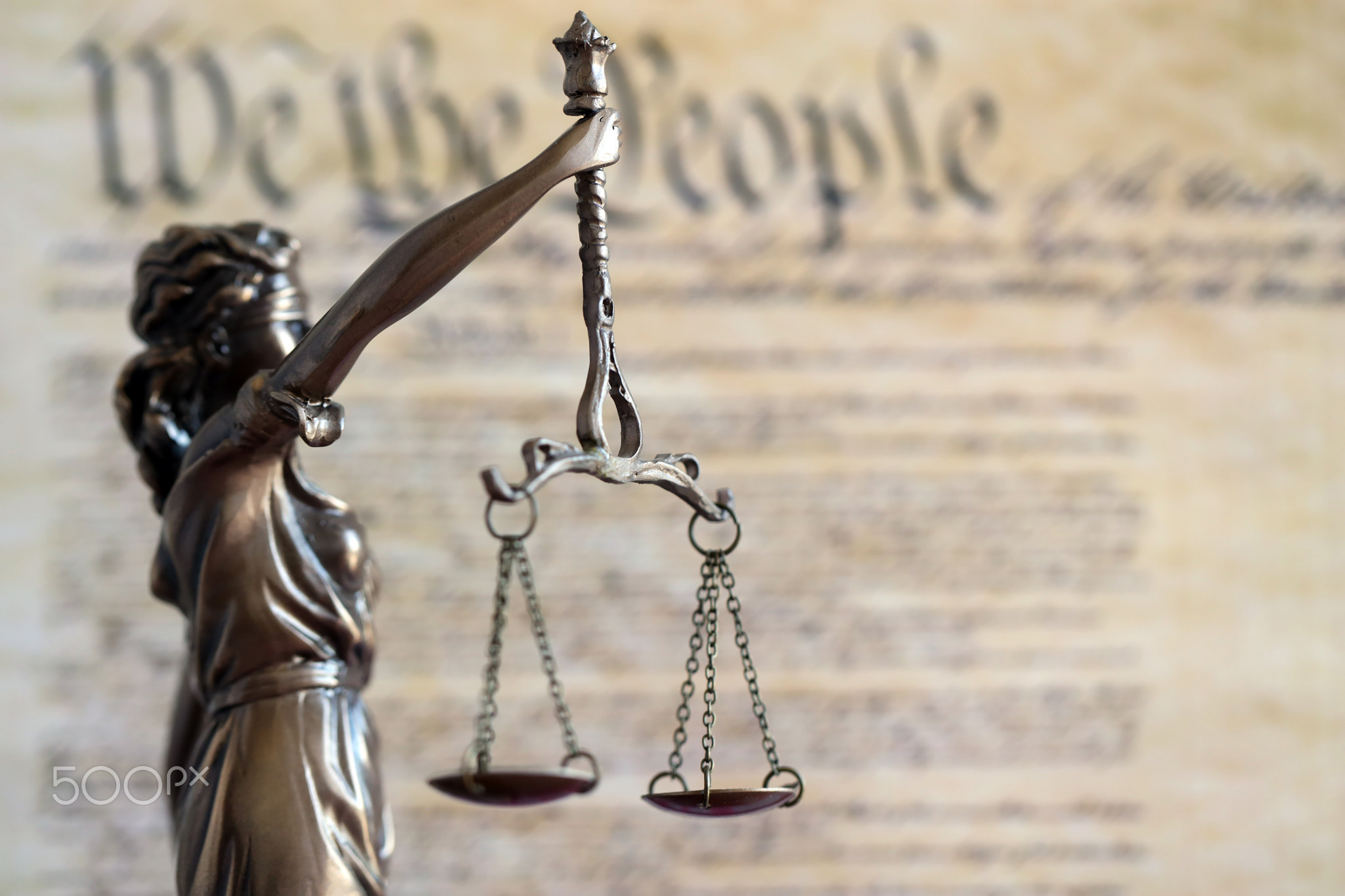 Lady Justice statue with scales on background of US Constitution. Lawsuit and punishment in US