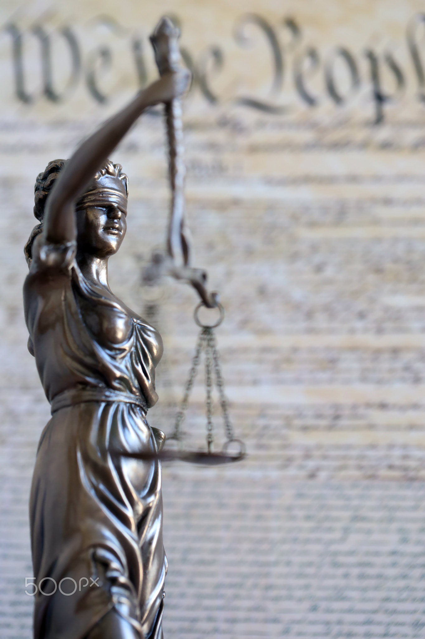 Lady Justice statue with scales on background of US Constitution. Lawsuit and punishment in US