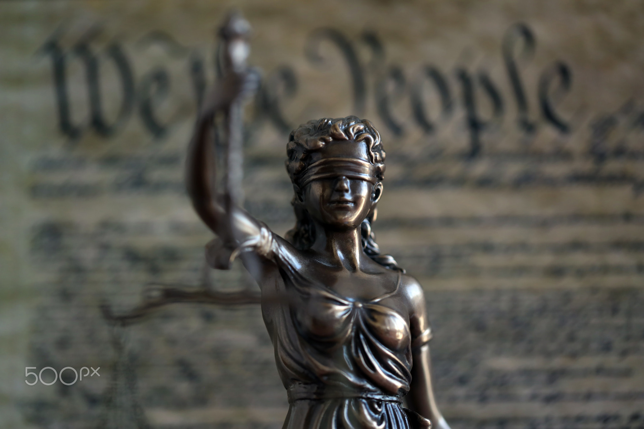 Low key scene with Lady Justice and backdrop of US Constitution page close up. Lawsuit and judgement