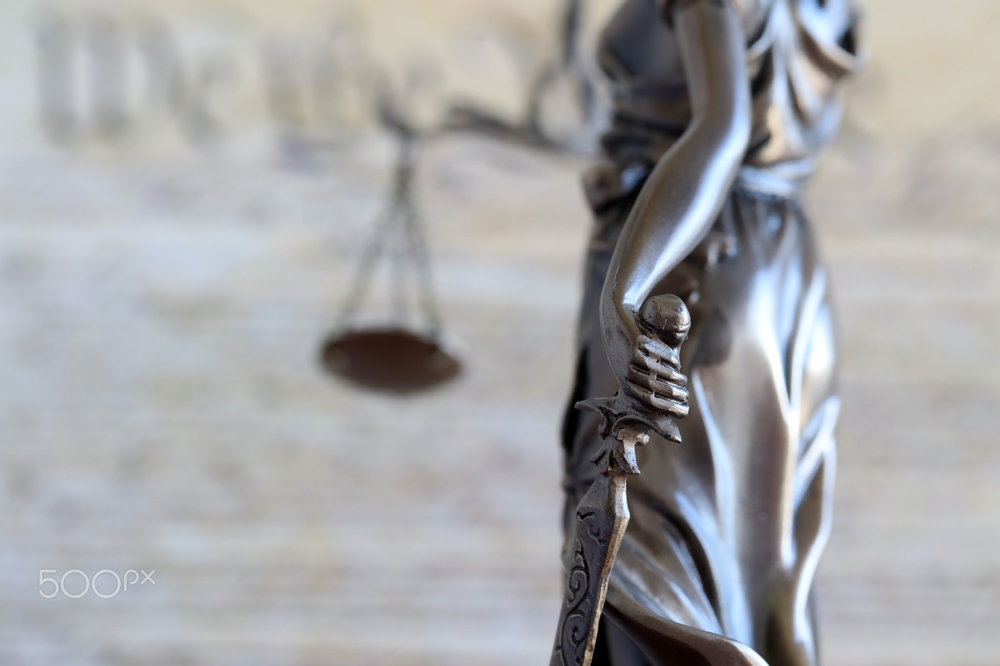 Lady Justice bronze statue and US Constitution blurred page close up. Lawsuit and punishment