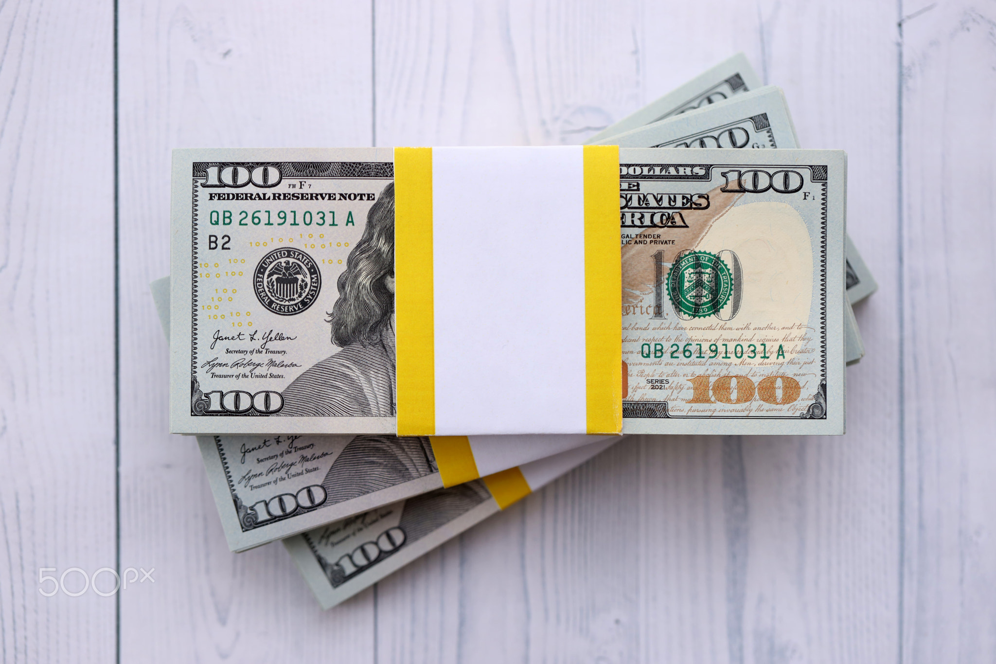 Three packs of ten thousand US dollar bills on wooden background. Packs of hundred dollar bills