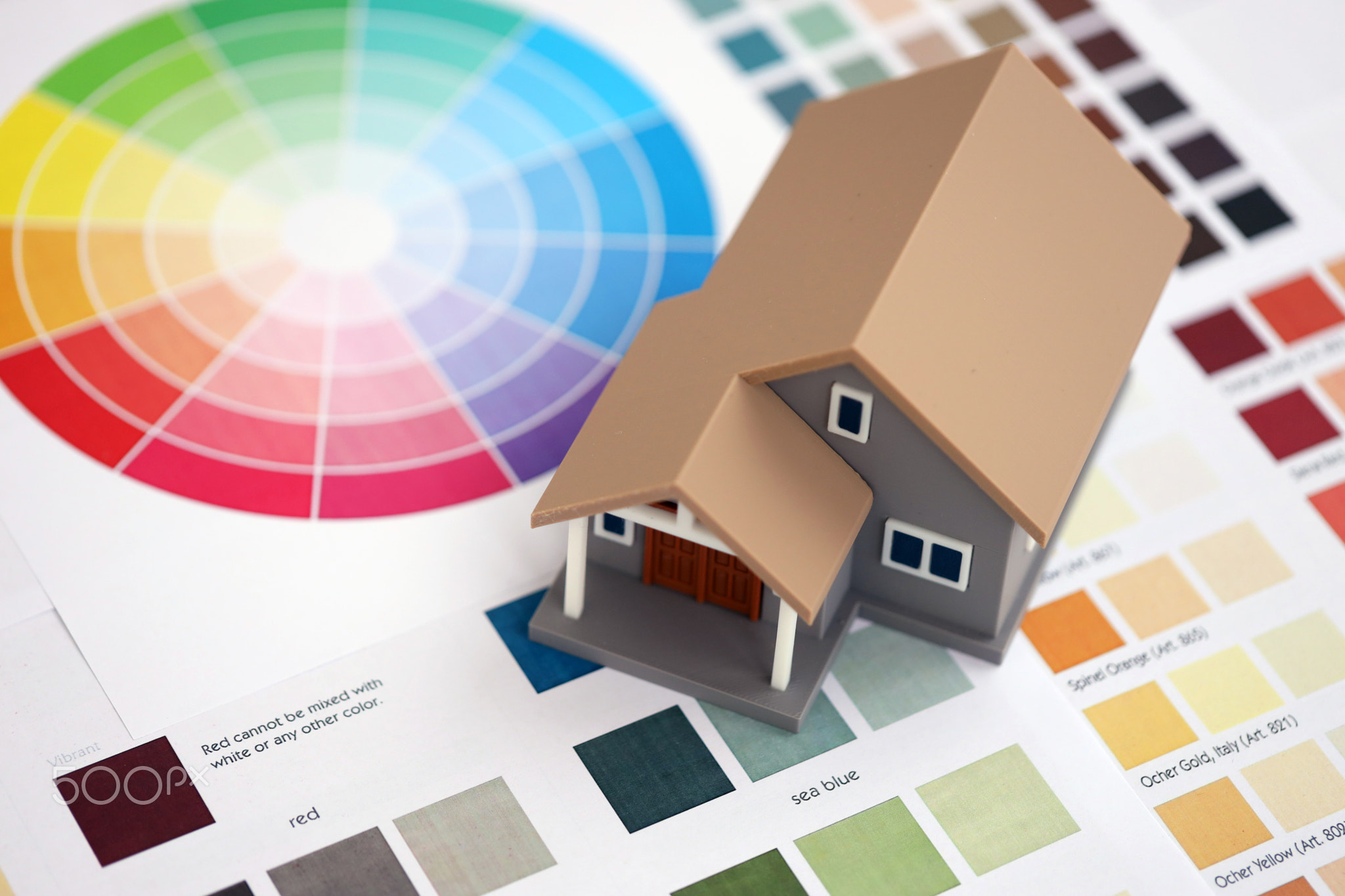 Small toy house and papers with color palette samples. Concept of interior and exterior design
