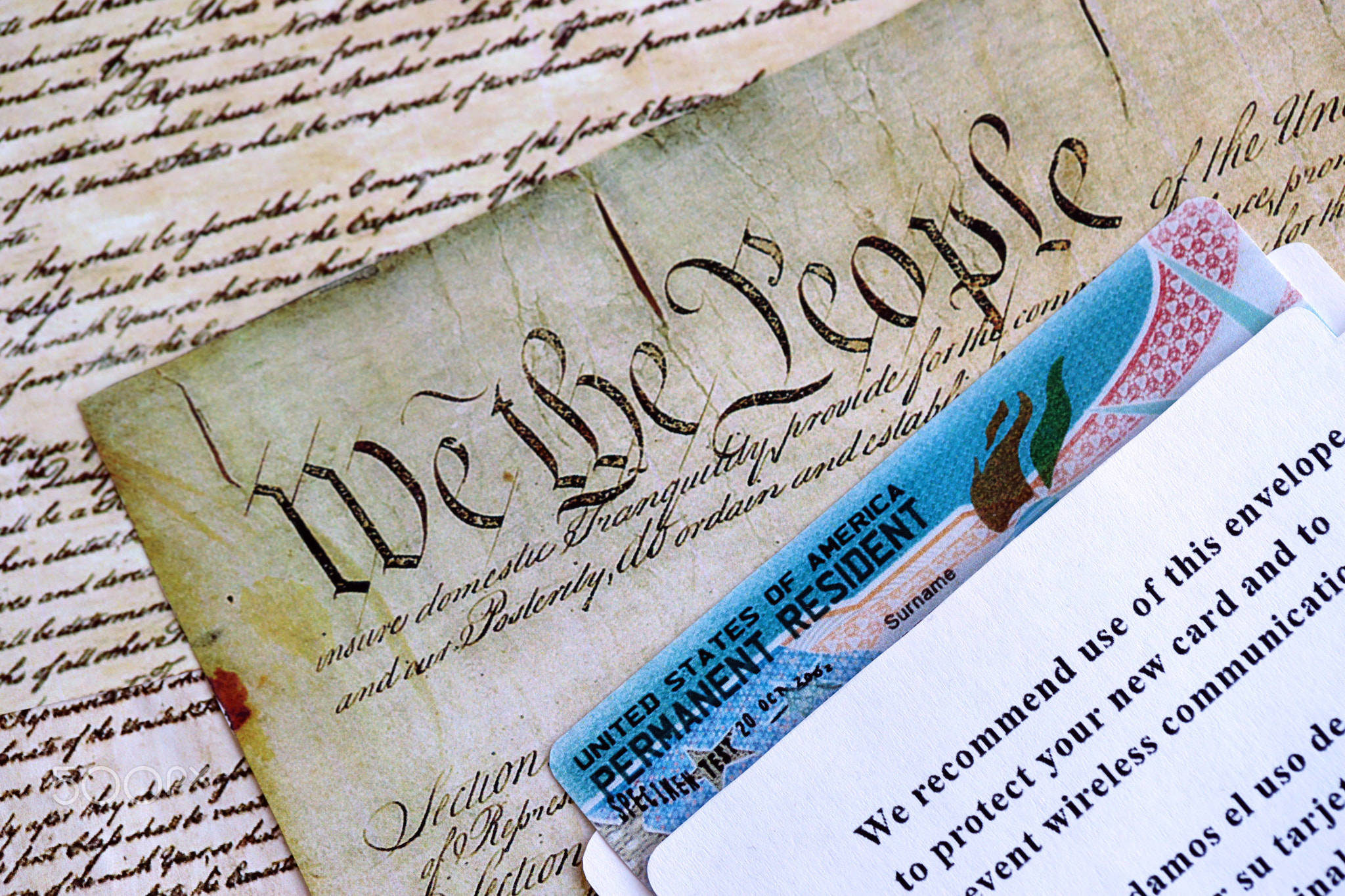 Permanent resident green card in envelope lies on US constitution page