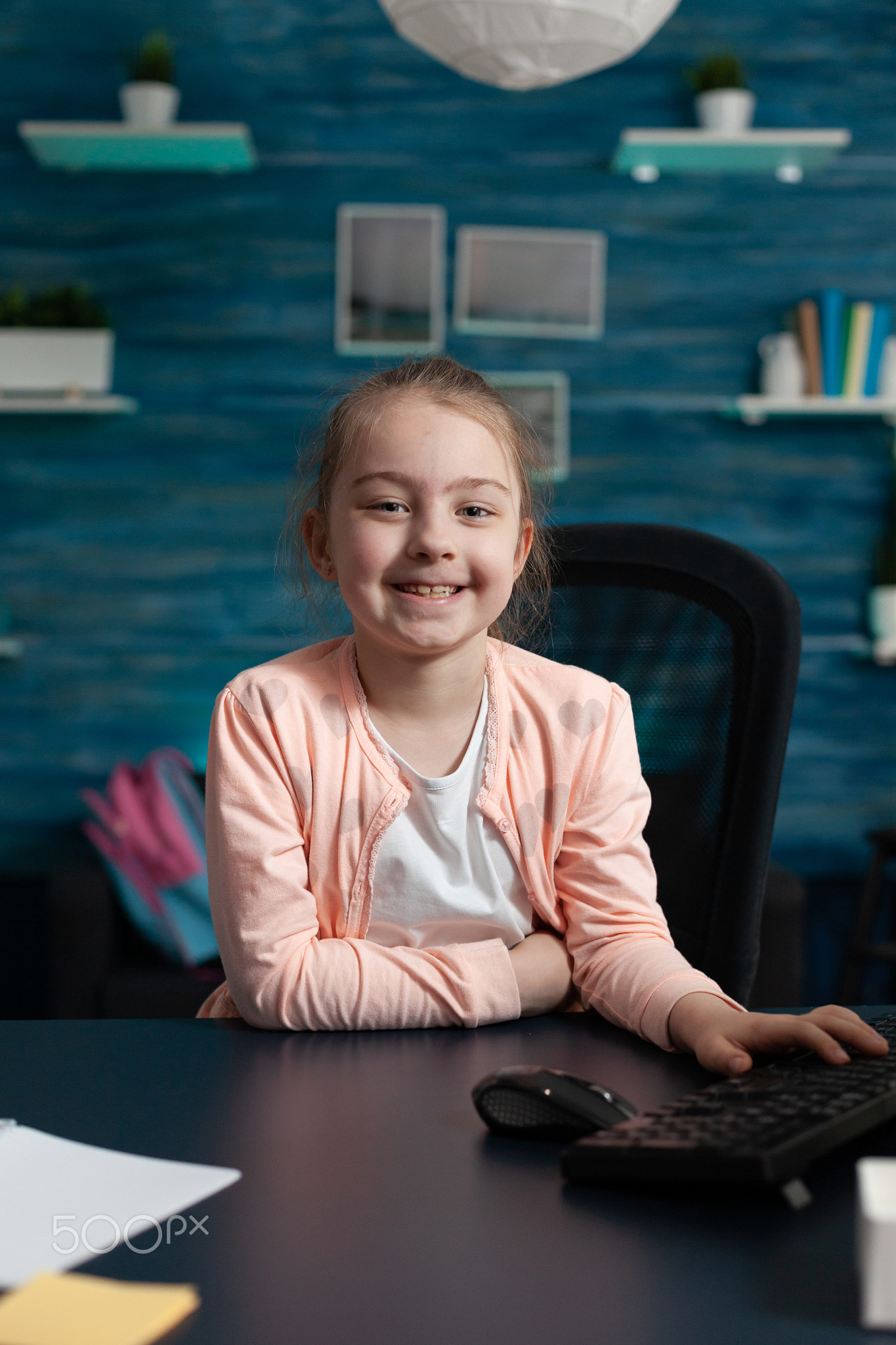 Portrait of little primary school kid sitting at home desk