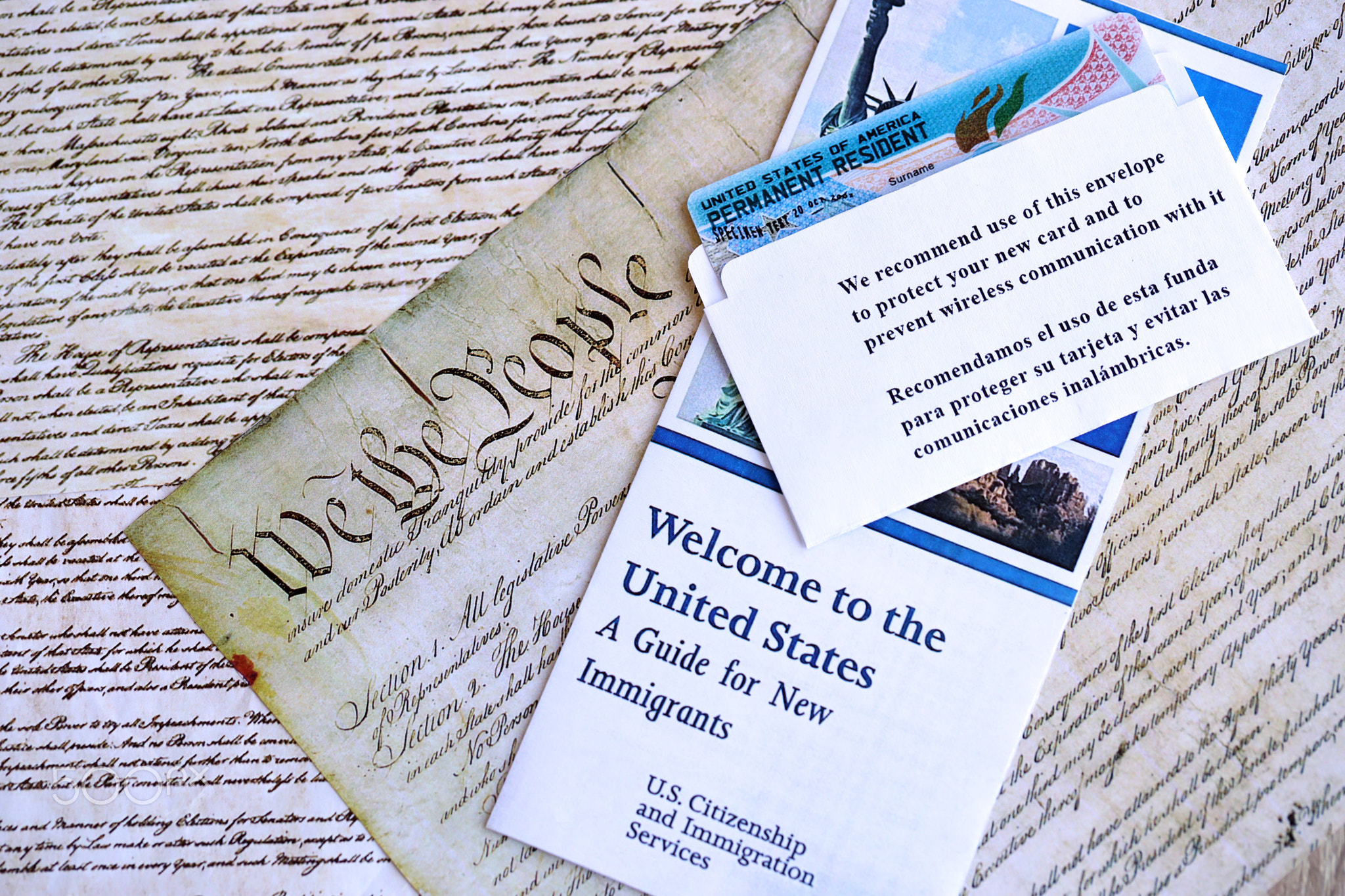 Permanent resident green card in envelope lies on US constitution page