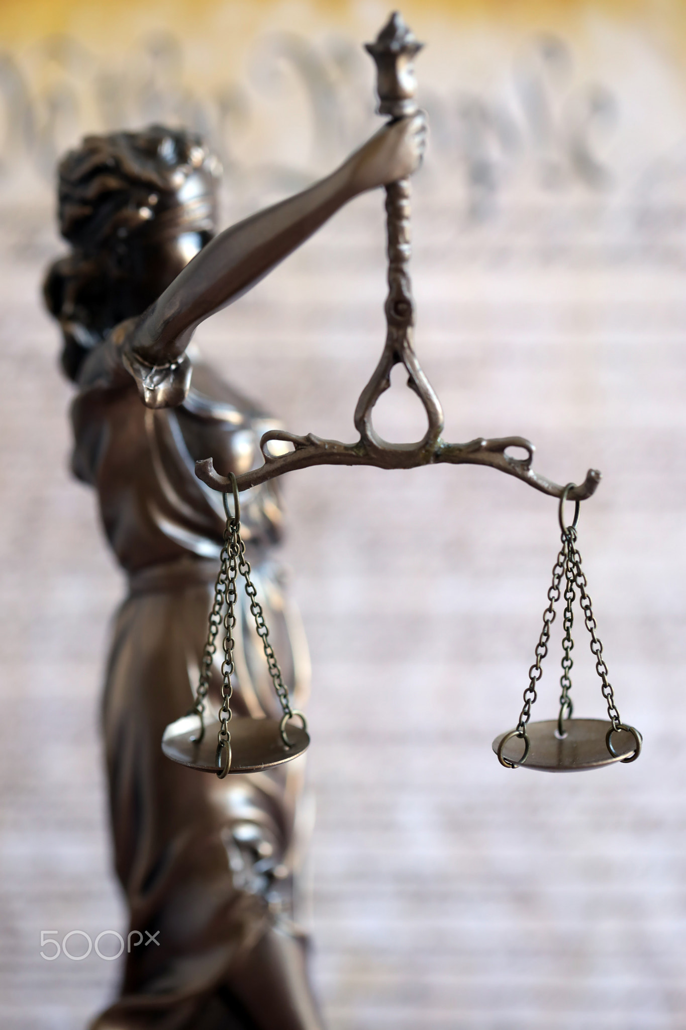 Lady Justice bronze statue and US Constitution blurred page close up. Lawsuit and punishment