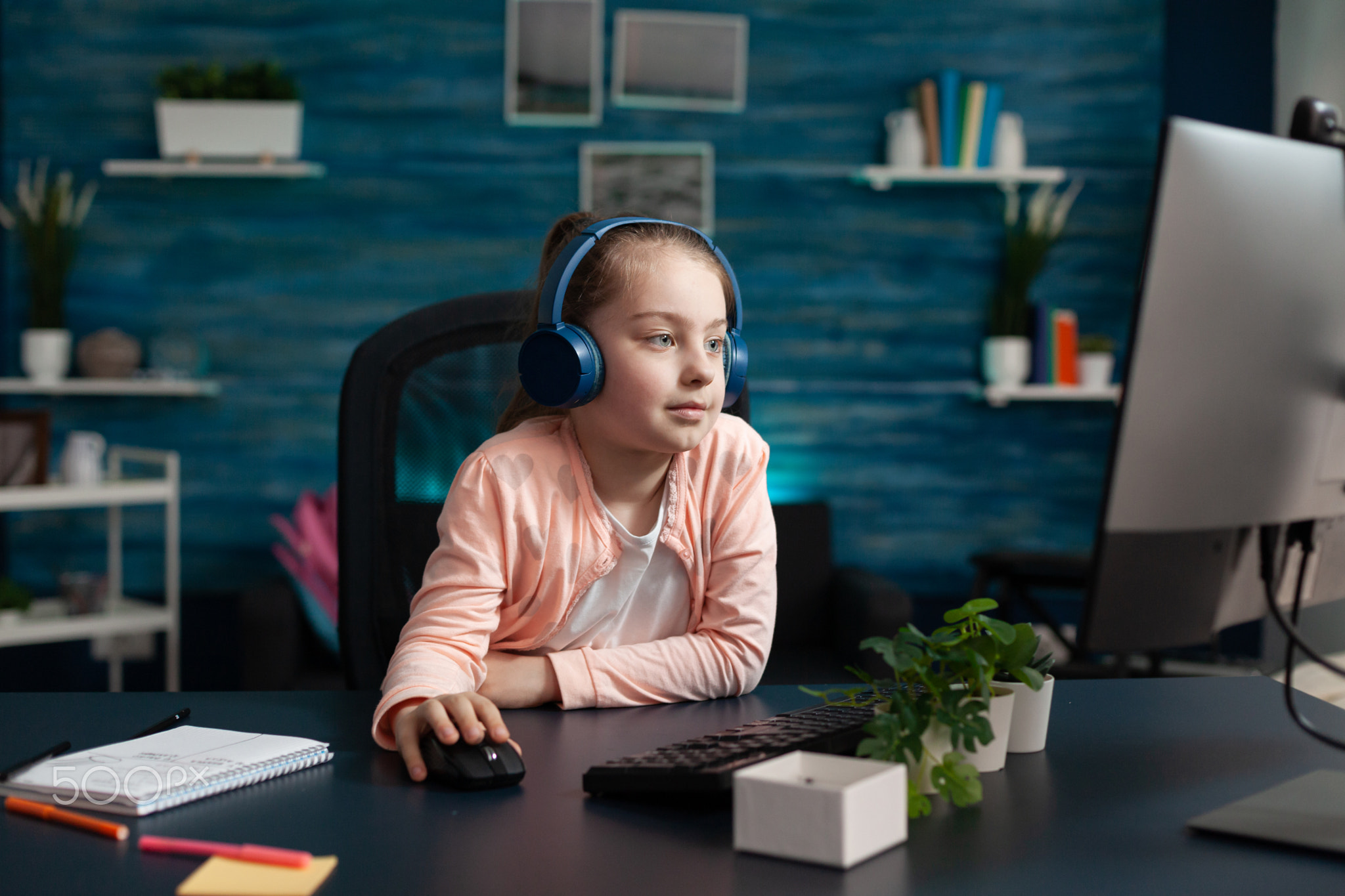Clever school girl using computer monitor at home