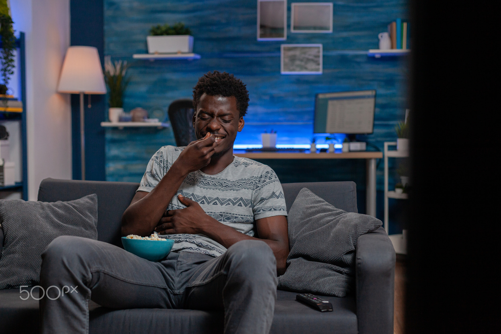 African american guy watching entertainment movie on television laughing