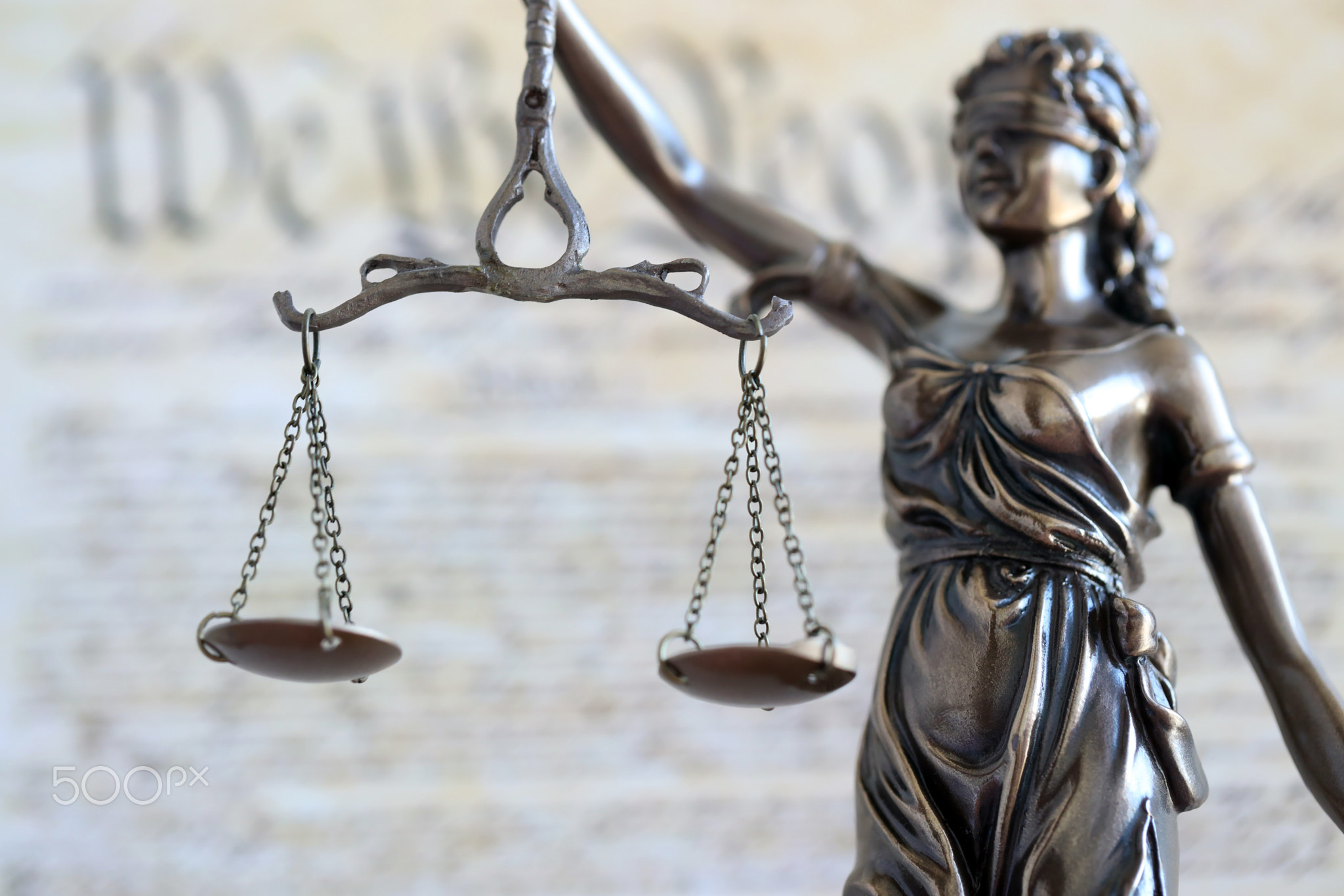The statue of justice Themis, the blindfolded goddess of justice against US Constitution page