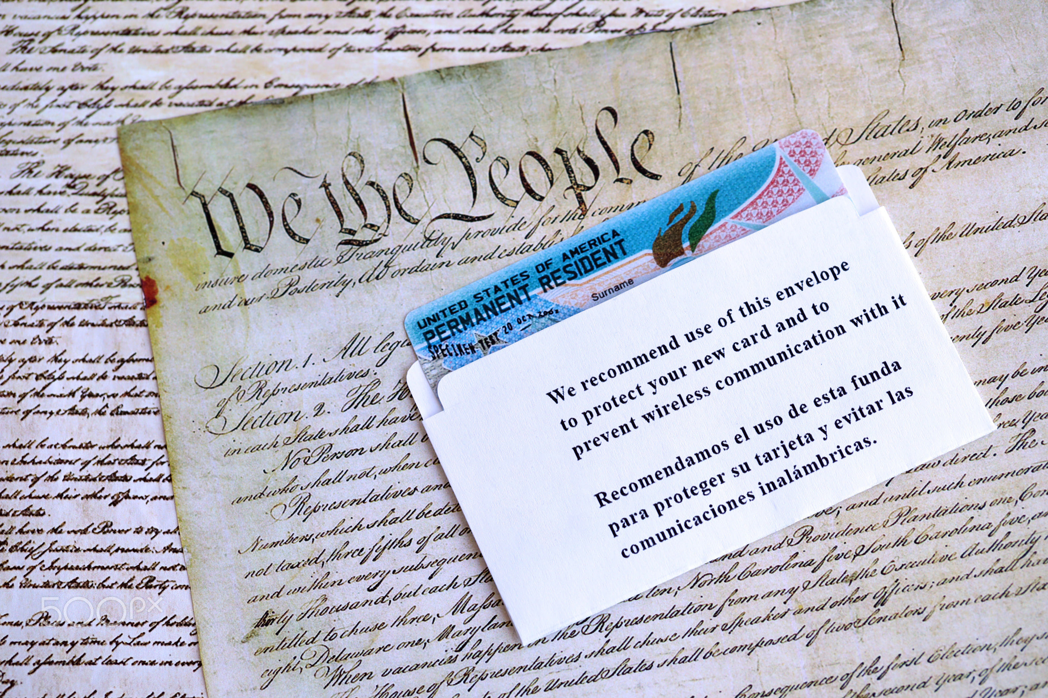 Permanent resident green card in envelope lies on US constitution page