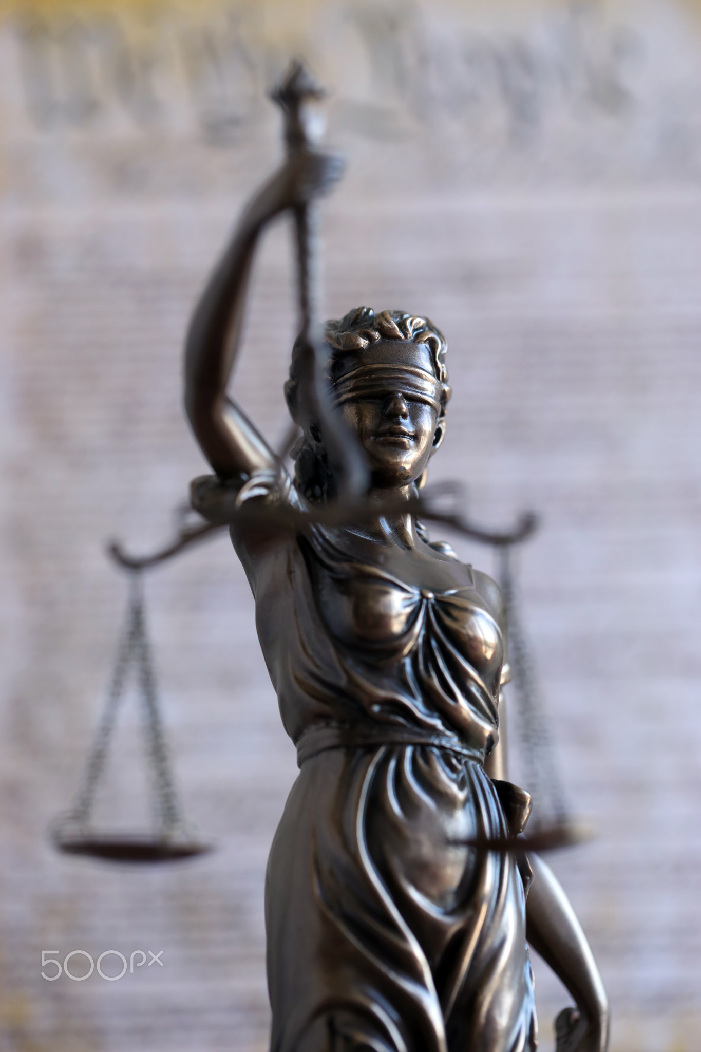 Lady Justice bronze statue and US Constitution blurred page close up. Lawsuit and punishment