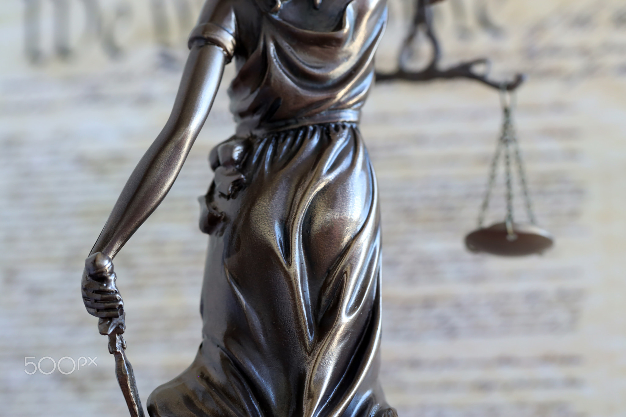 Lady Justice bronze statue and US Constitution blurred page close up. Lawsuit and justice in US
