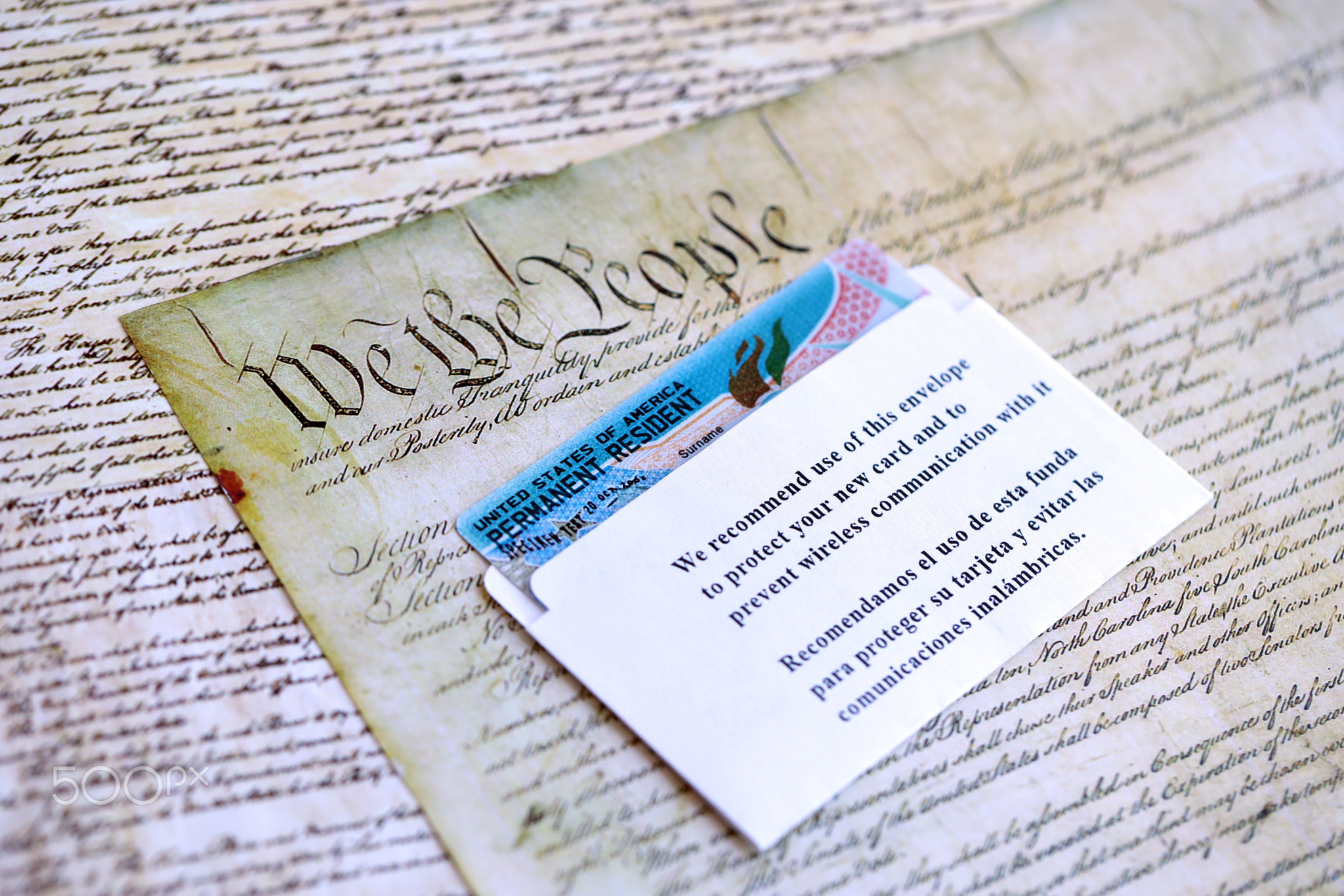 Permanent resident green card in envelope lies on US constitution page