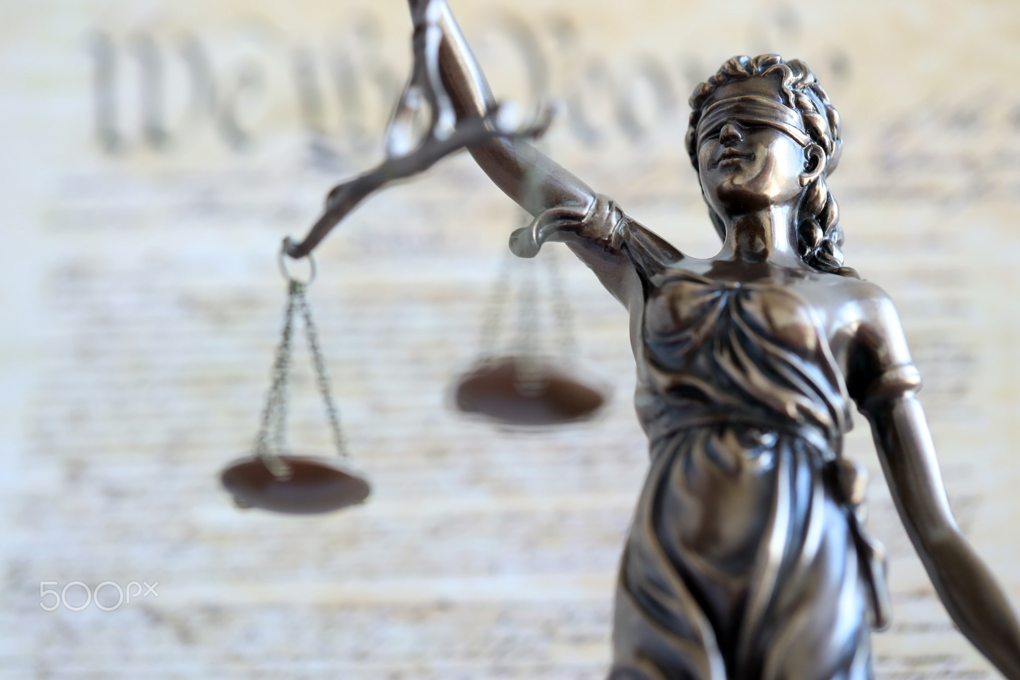 Lady Justice statue with scales on background of US Constitution page. Lawsuit and punishment in US