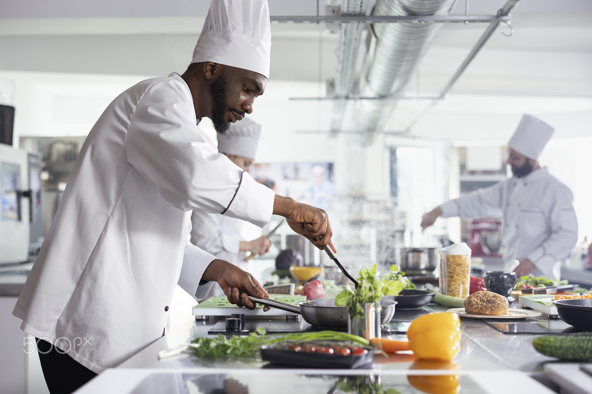 African American head chef cooking a savory dish in a stainless steel pan