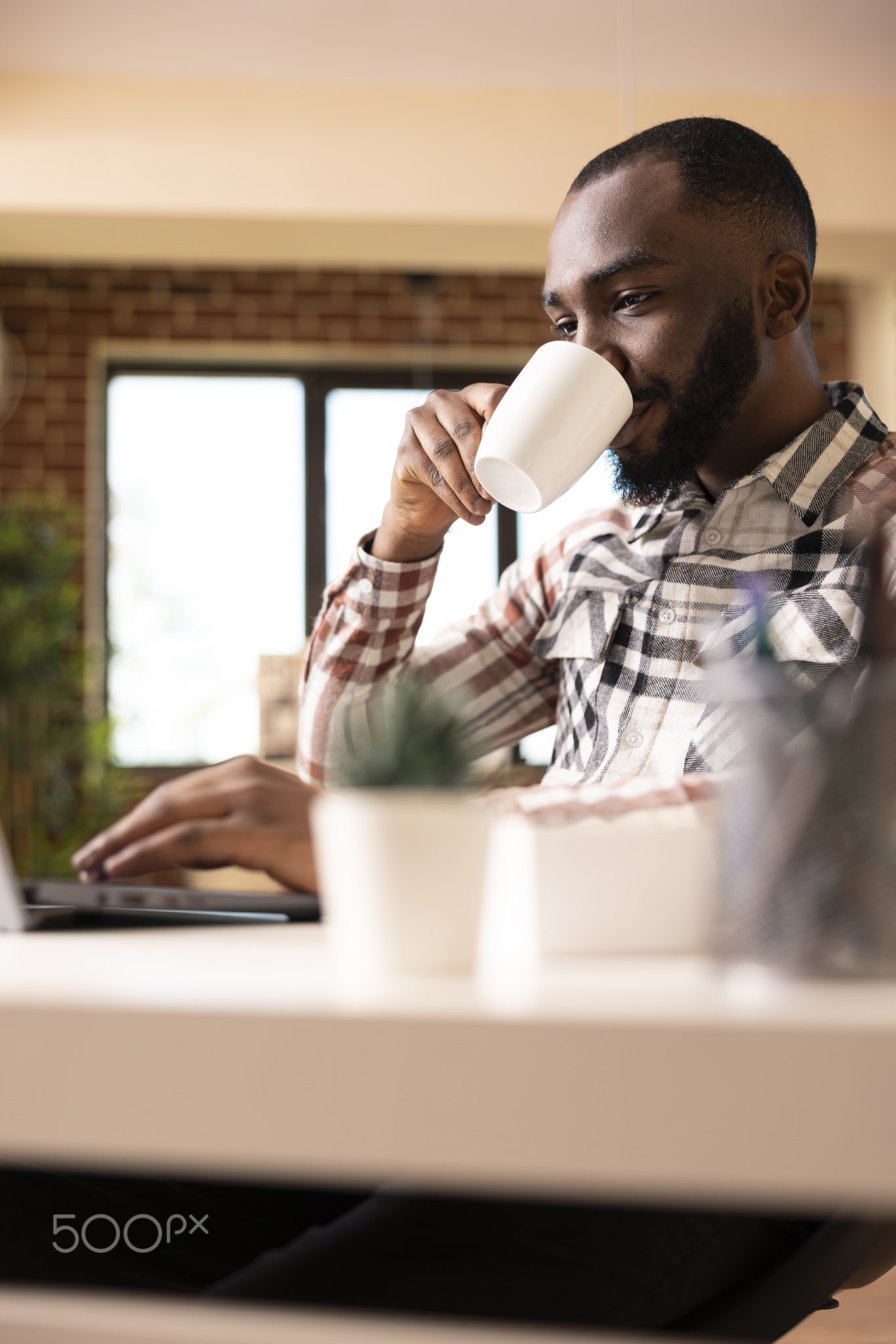 Entrepreneur drinking coffee and reading online articles on laptop