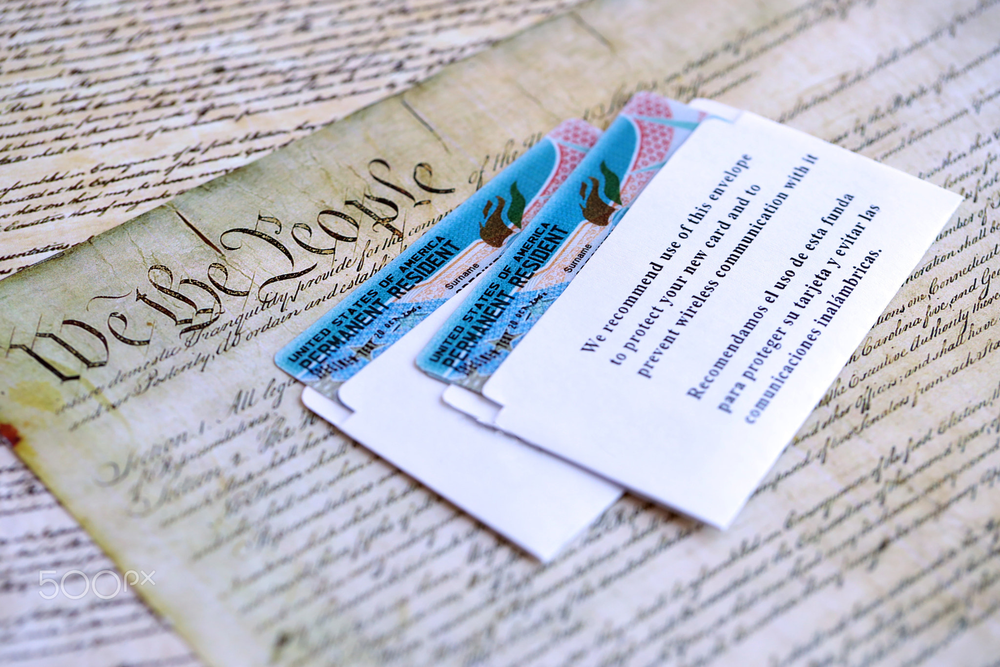 Permanent resident green card in envelope lies on US constitution page