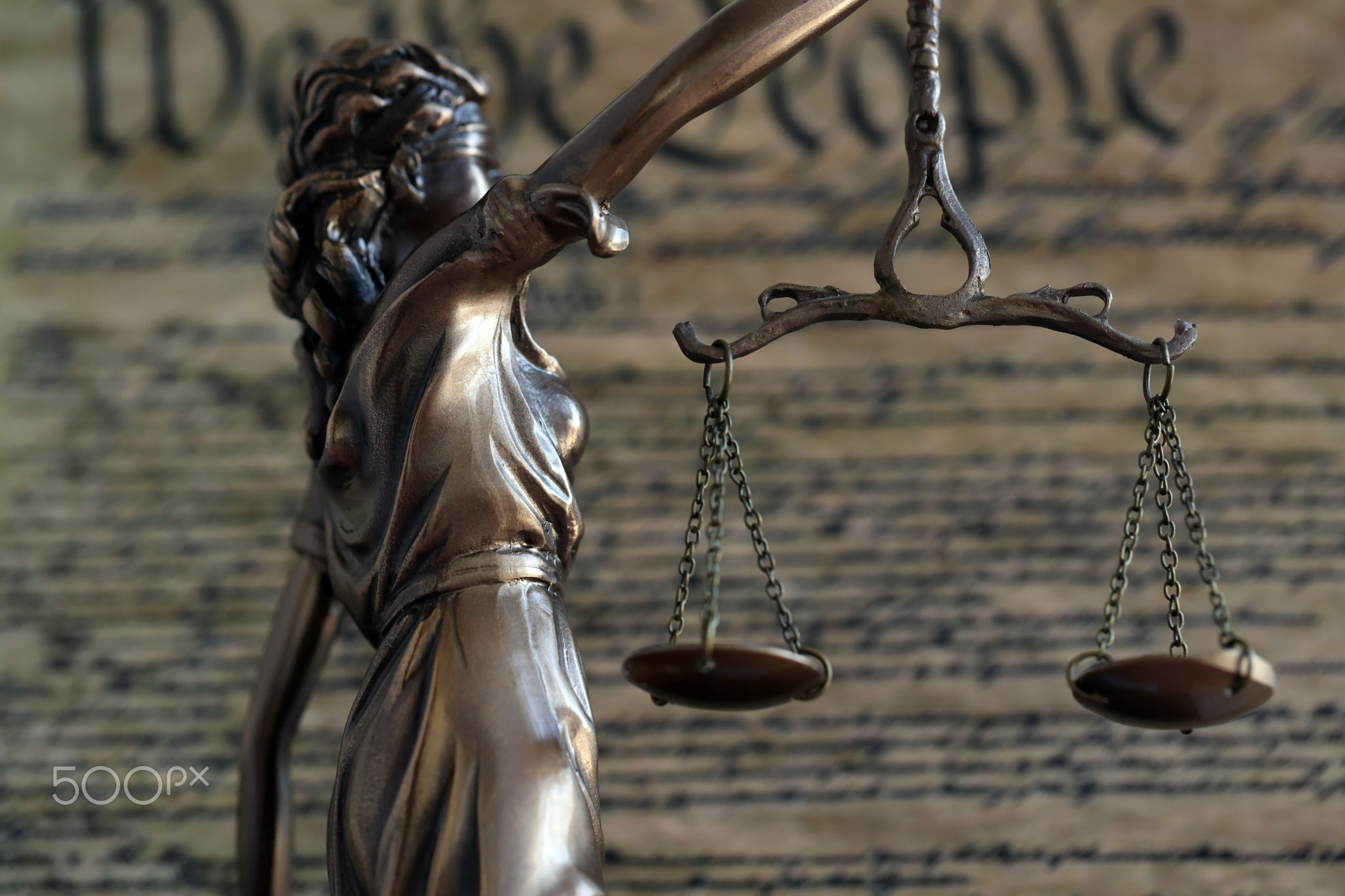 Dark scene with Lady Justice and background of blurred US Constitution page