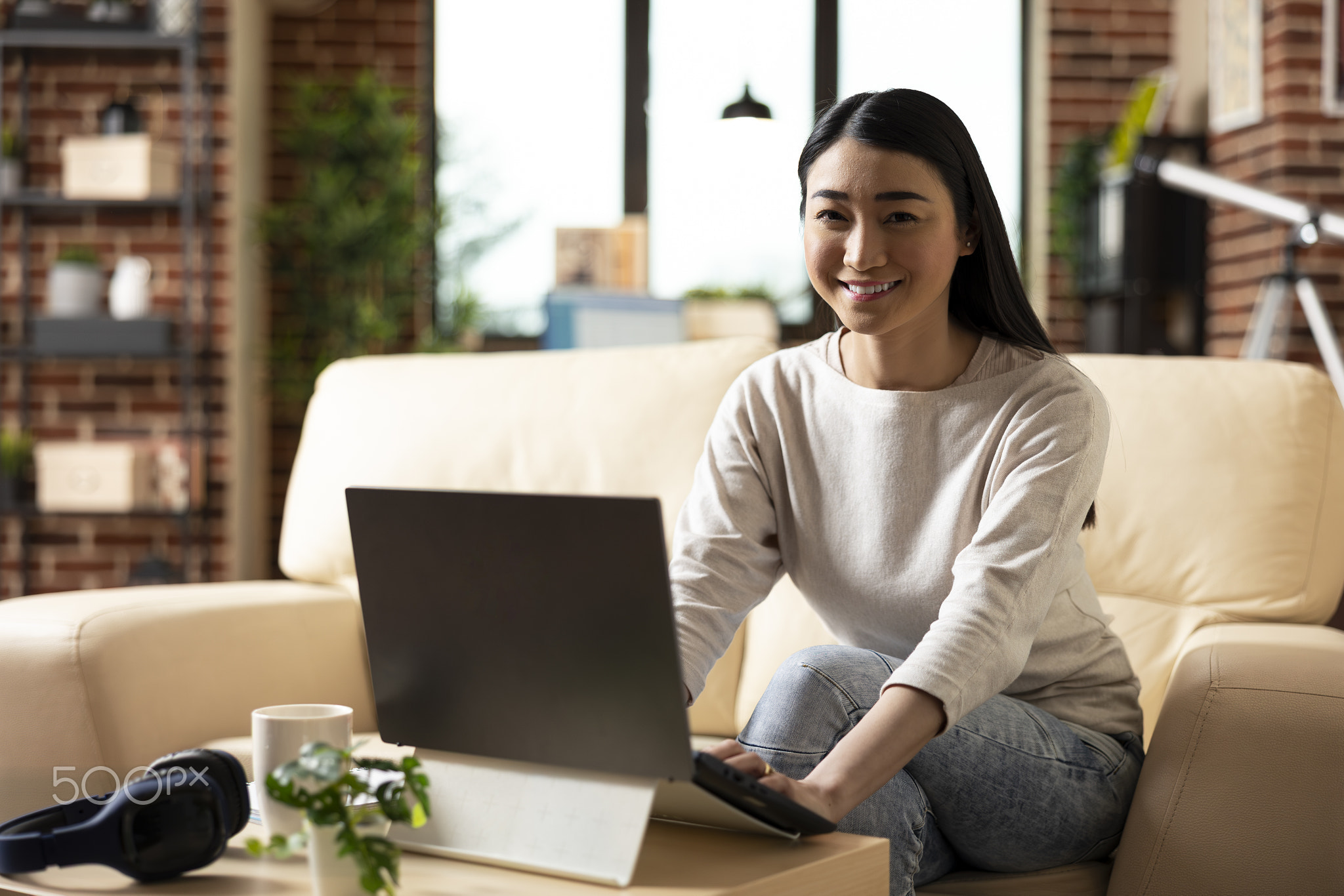 Happy businesswoman using laptop in apartment