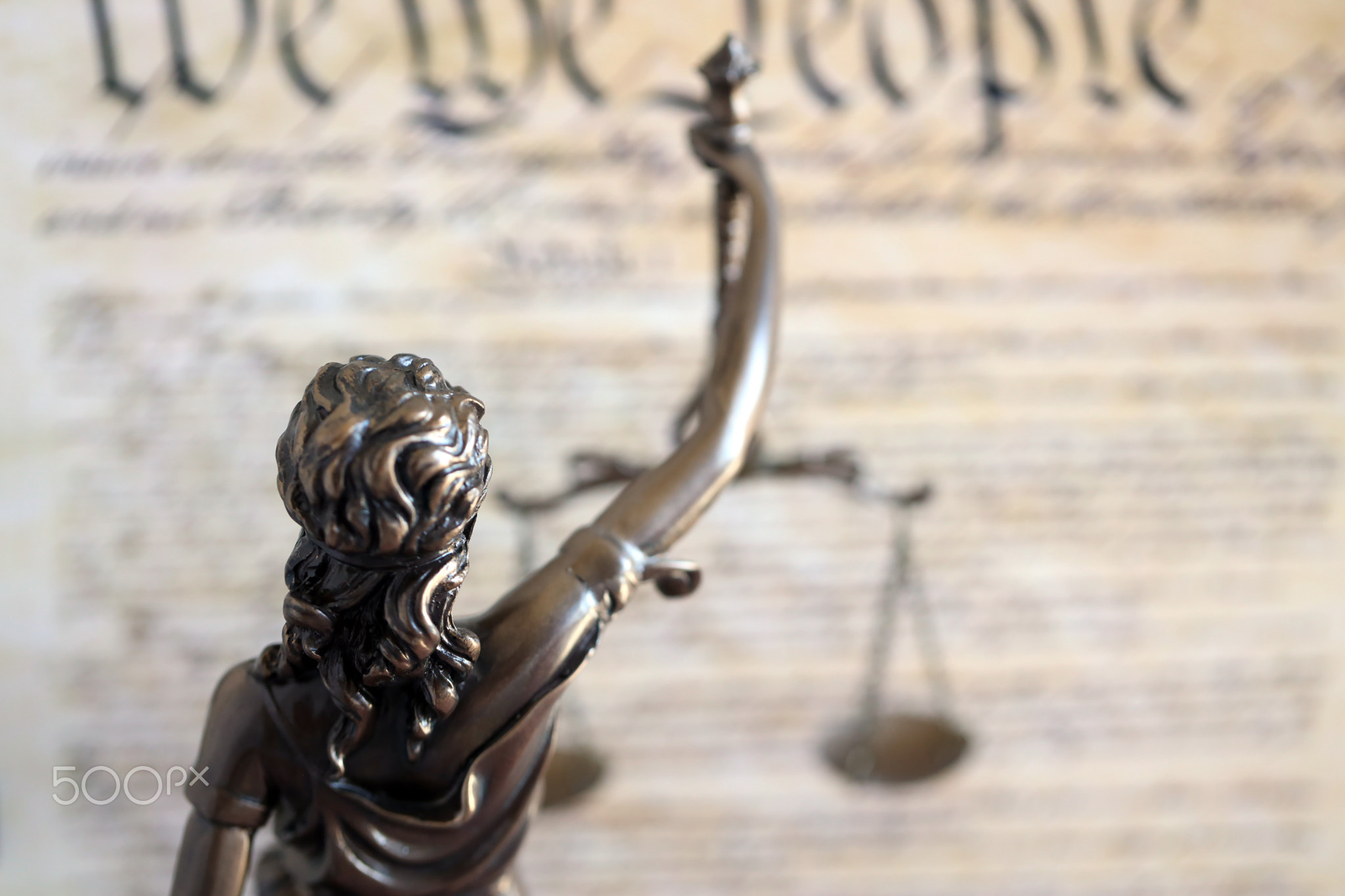 Lady Justice statue with scales on background of US Constitution. Lawsuit and punishment in US