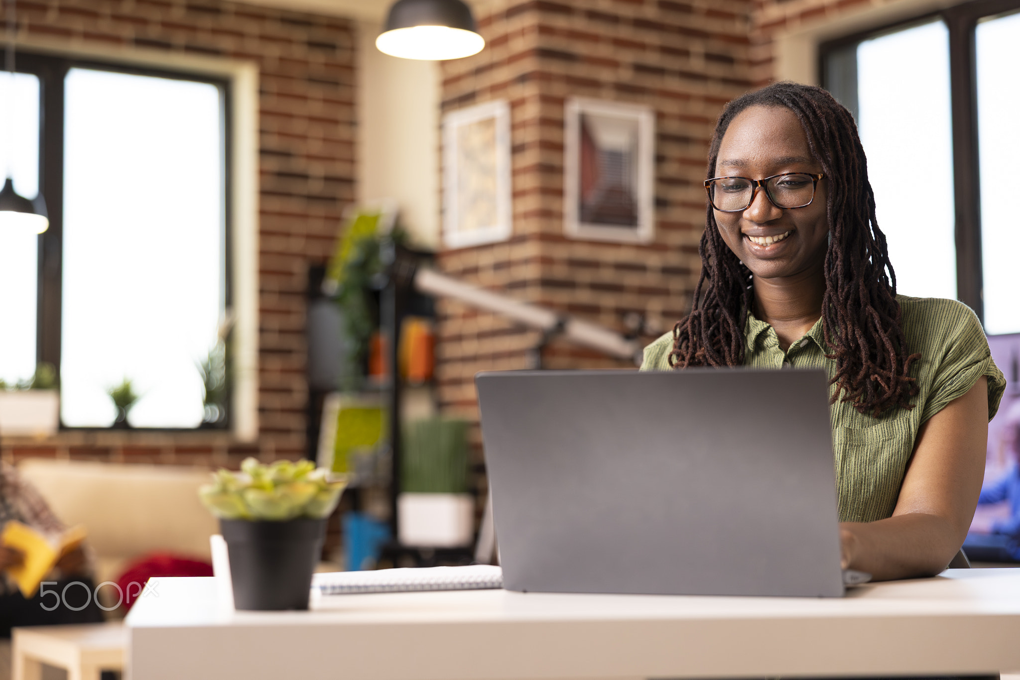 Smiling black woman reading online articles on laptop