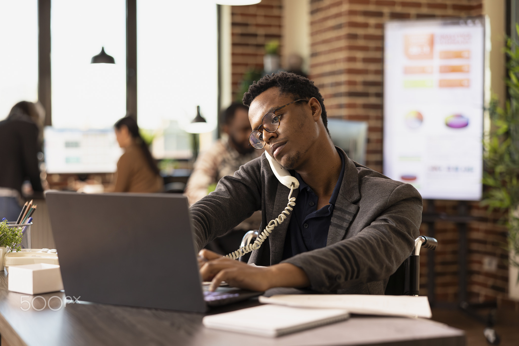 Businessman using landline and laptop