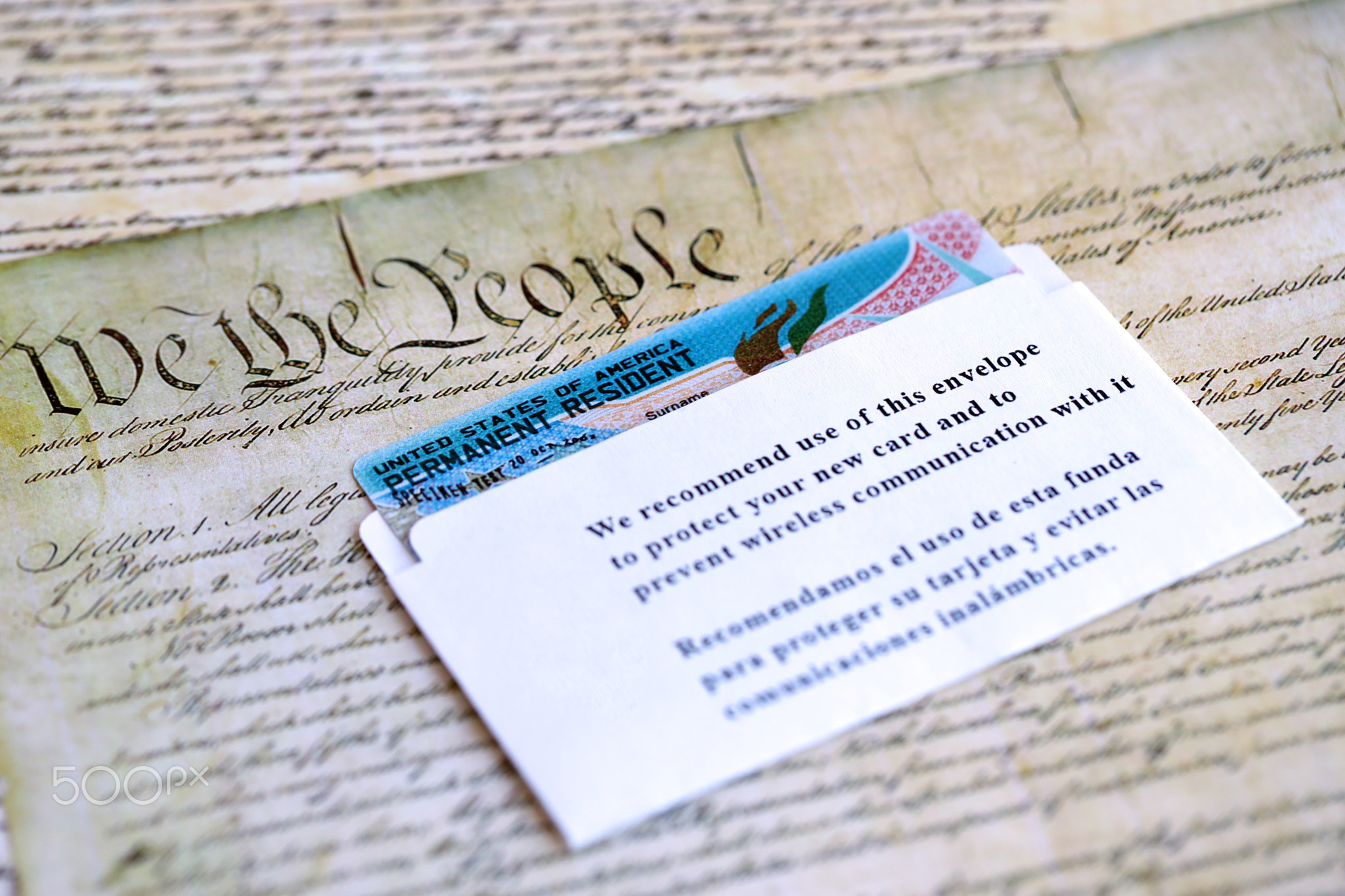 Permanent resident green card in envelope lies on US constitution page