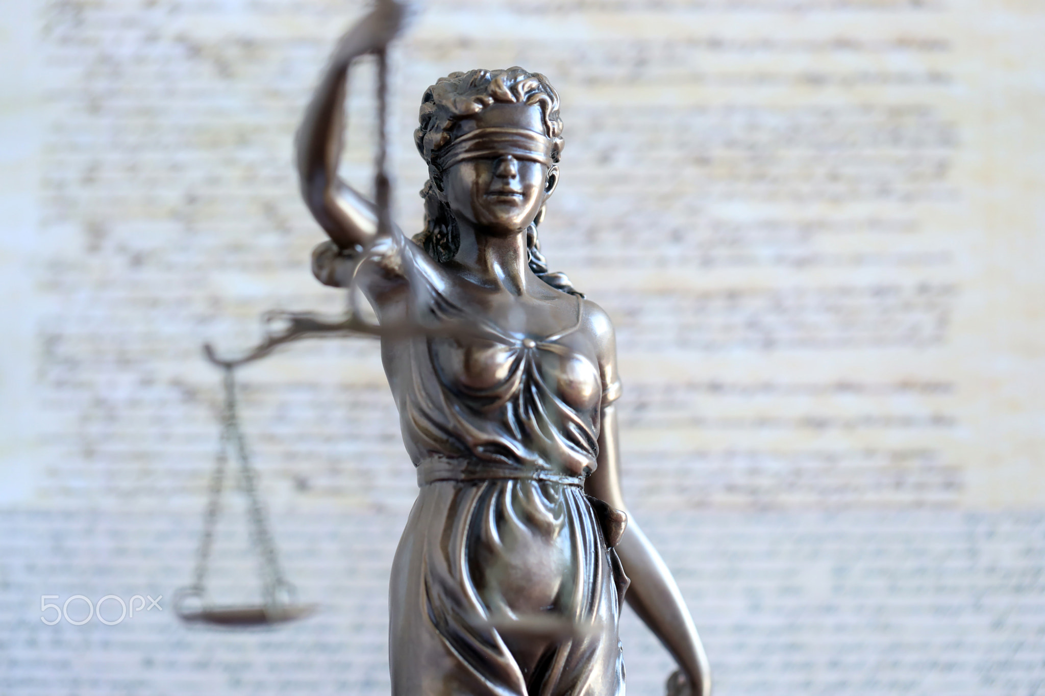 Lady Justice bronze statue and US Constitution blurred page close up. Lawsuit and justice in US