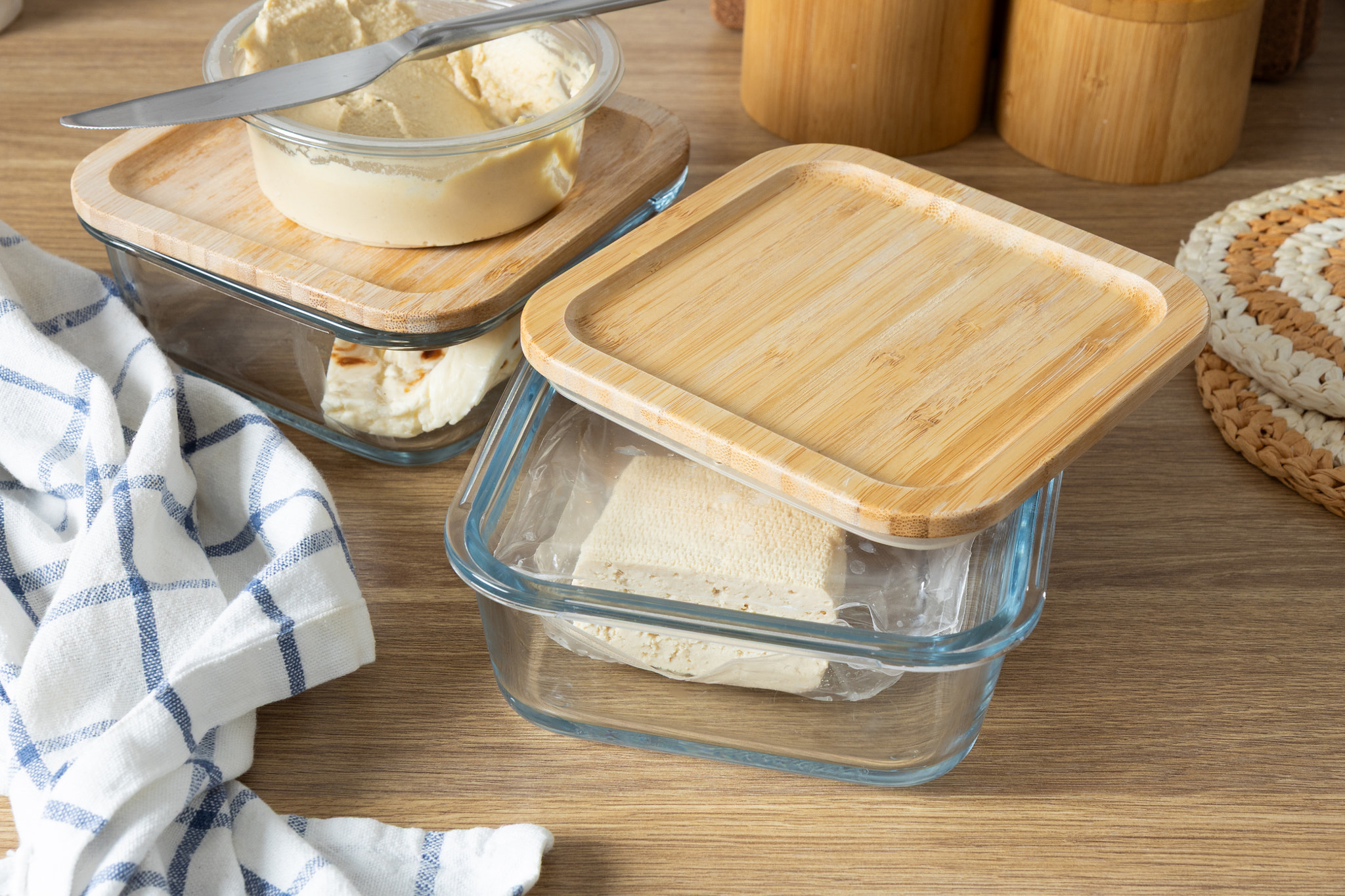 A set of clear glass food storage containers with wooden lids, neatly arranged on a wooden table