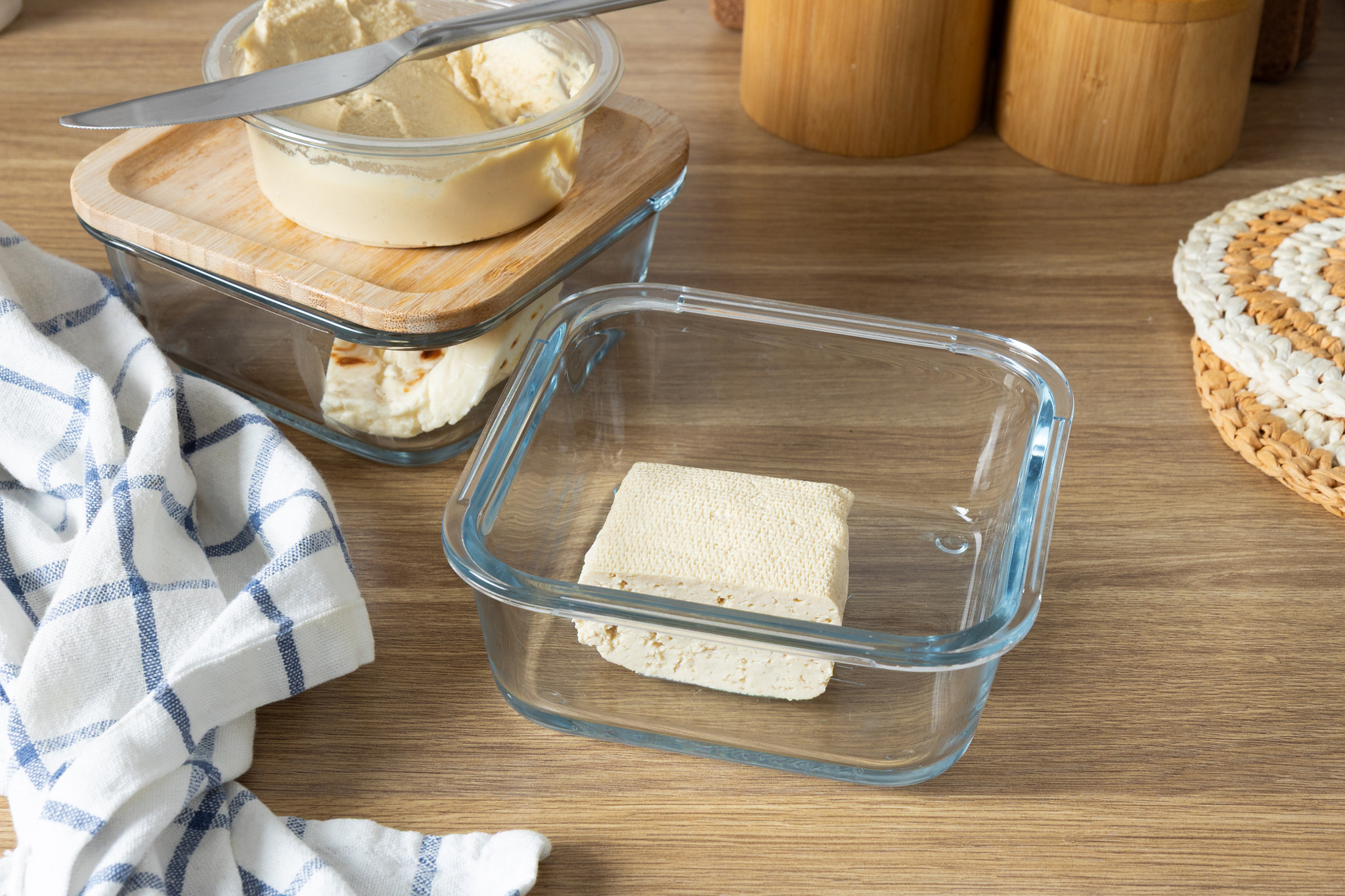 A set of clear glass food storage containers with wooden lids, neatly arranged on a wooden table
