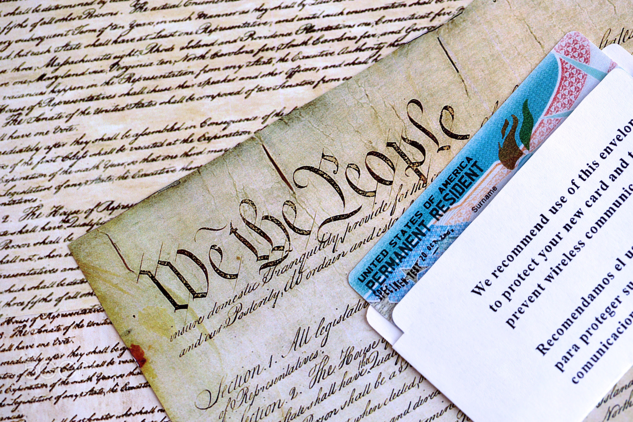 Permanent resident green card in envelope lies on US constitution page
