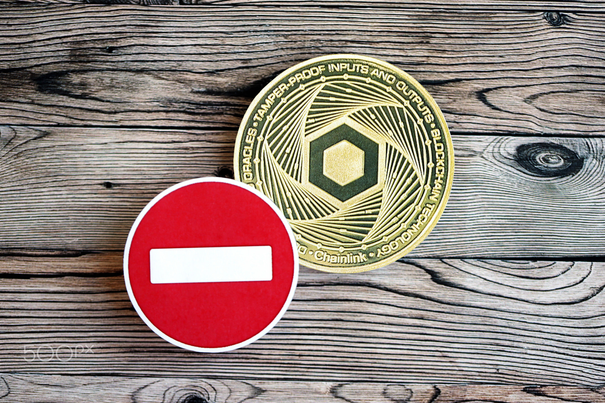 Chainlink LINK coin and red paper stop sign on wooden background