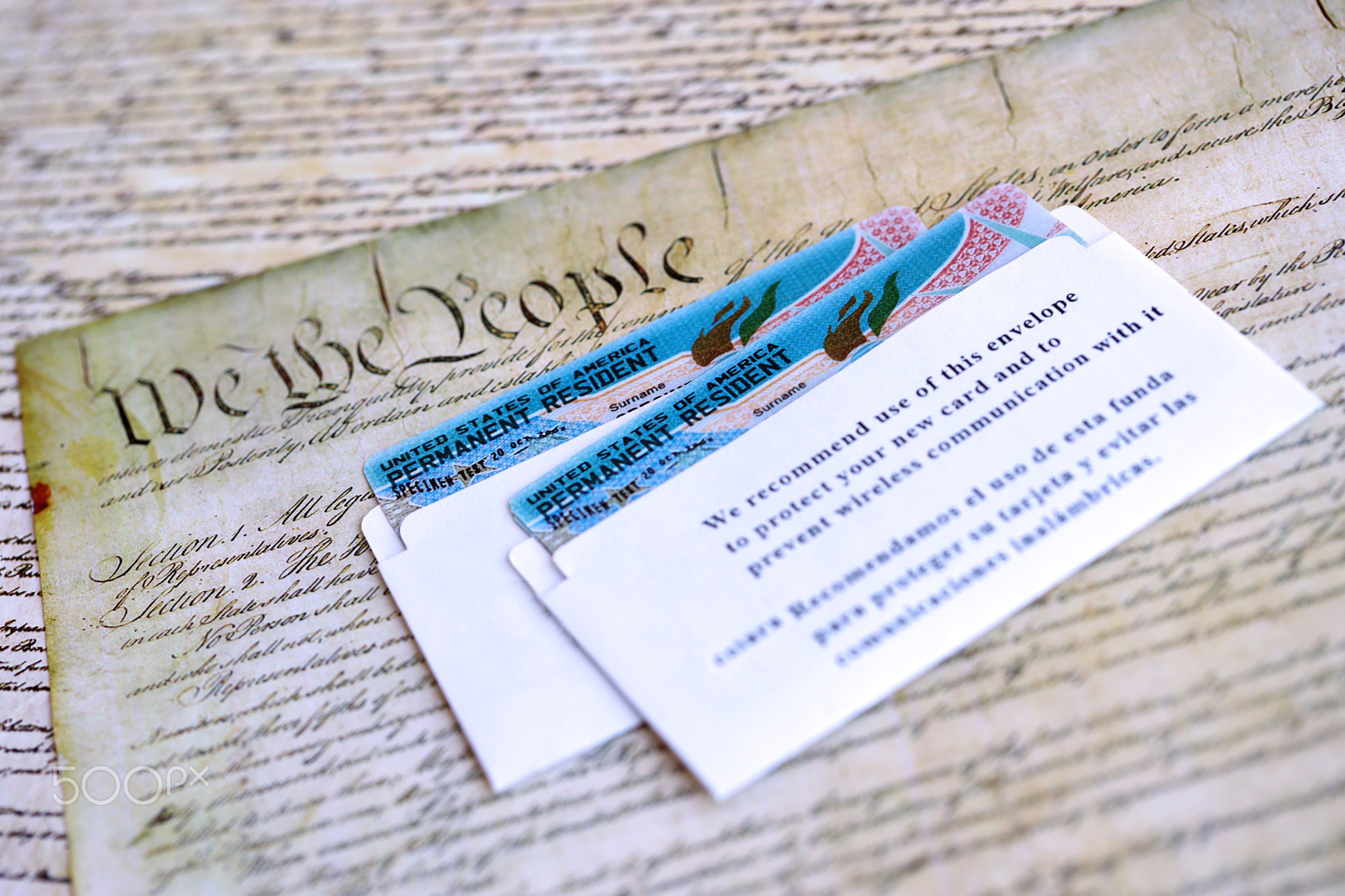 Permanent resident green card in envelope lies on US constitution page