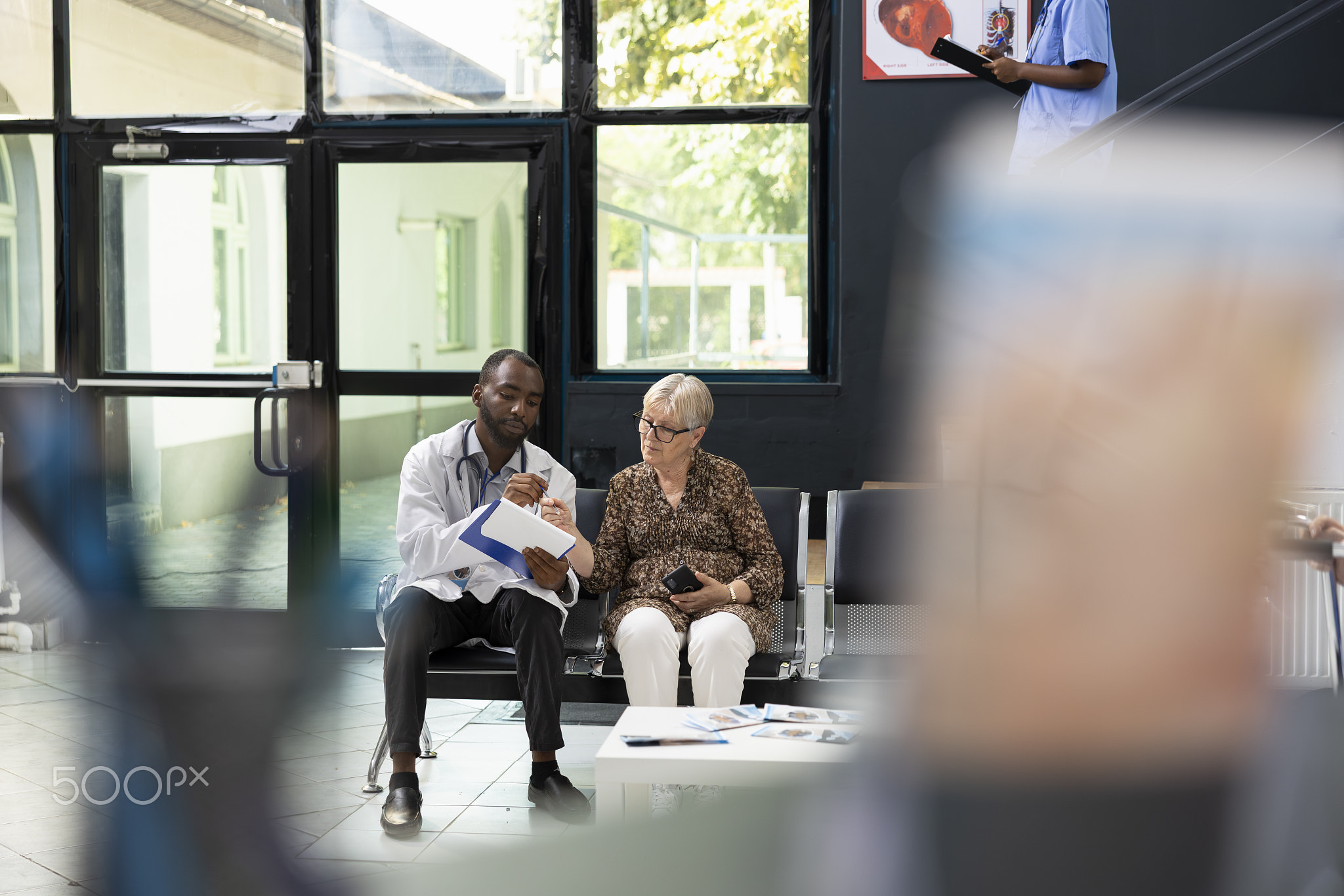 Elderly patient at consultation with black medic in modern clinic lobby