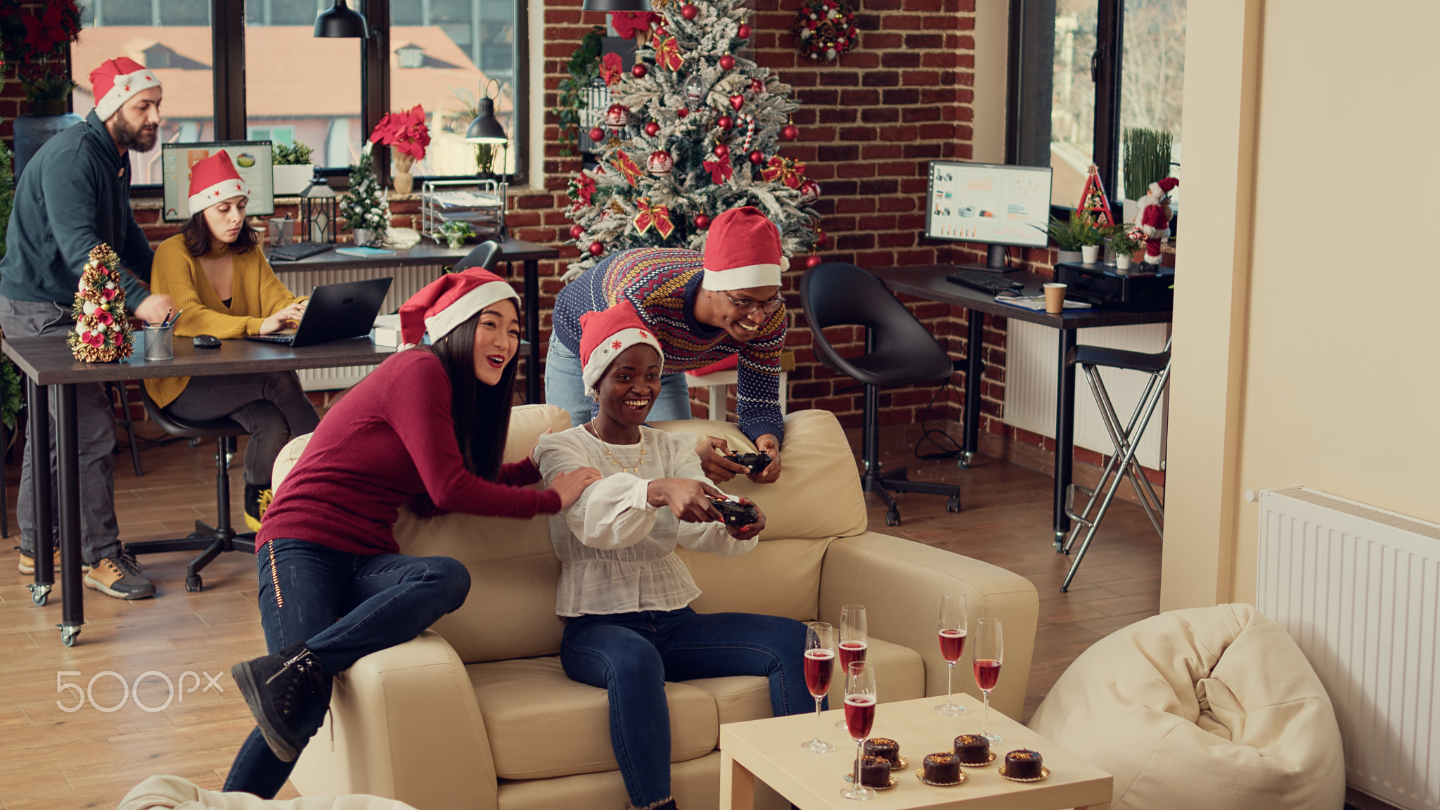Cheerful colleagues playing video games at christmas party in office