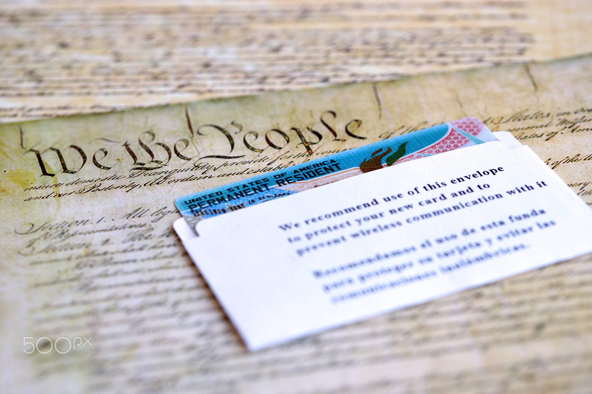 Permanent resident green card in envelope lies on US constitution page