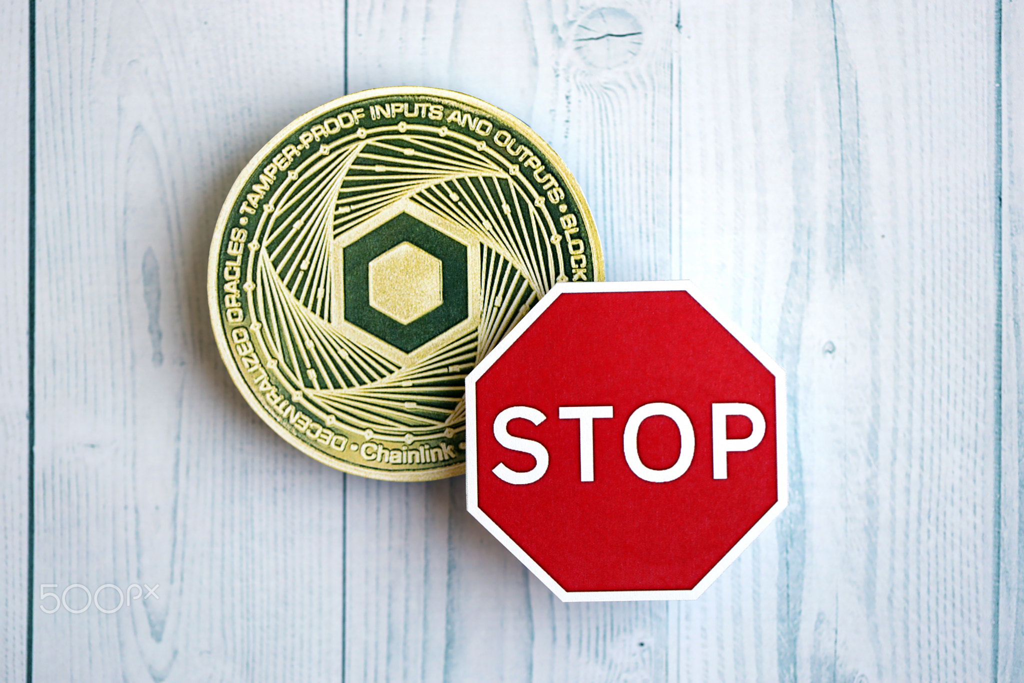 Chainlink LINK coin and red paper stop sign on wooden background