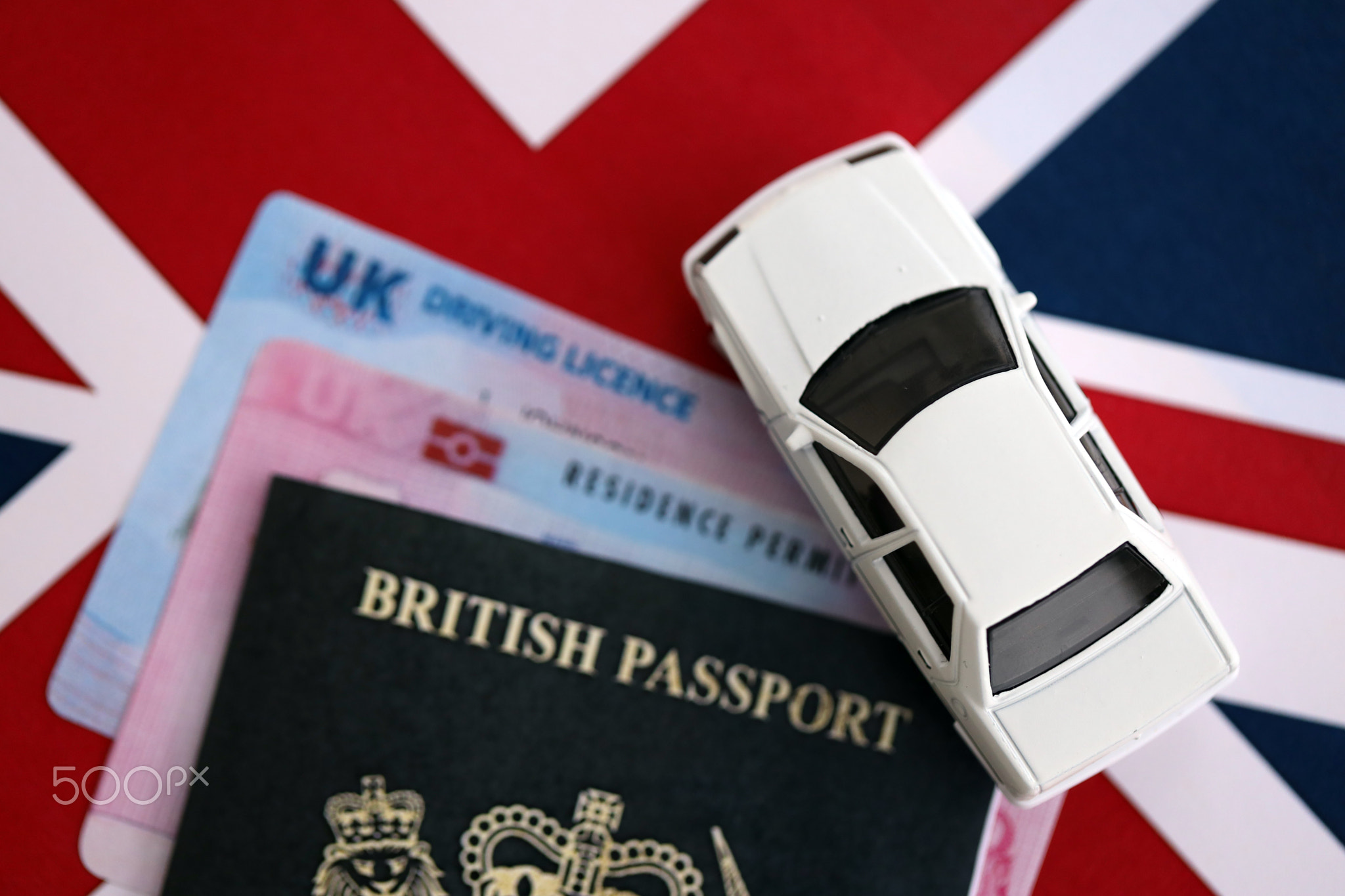 United Kingdom driving license with passport and residence permit card on UK flag