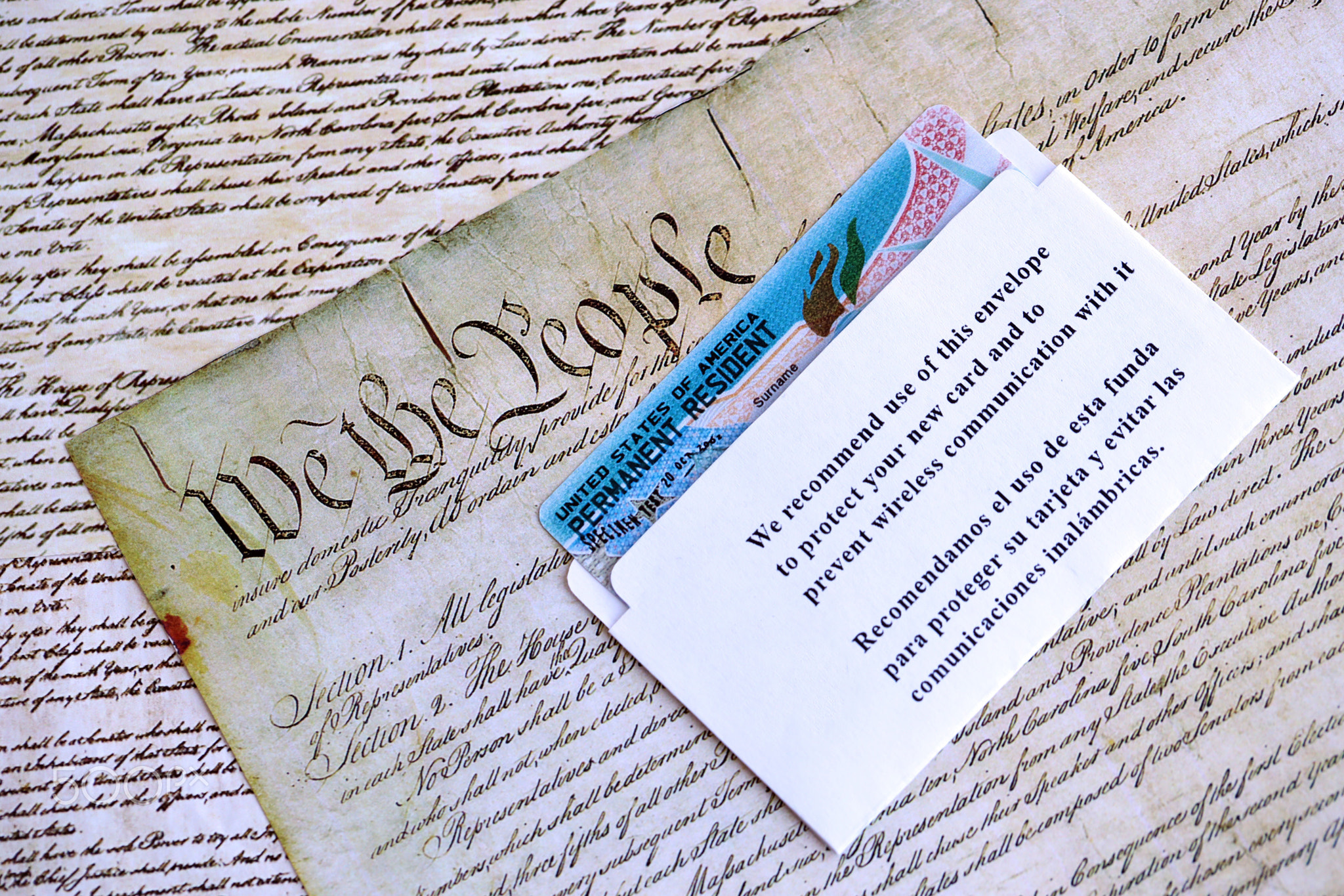 Permanent resident green card in envelope lies on US constitution page