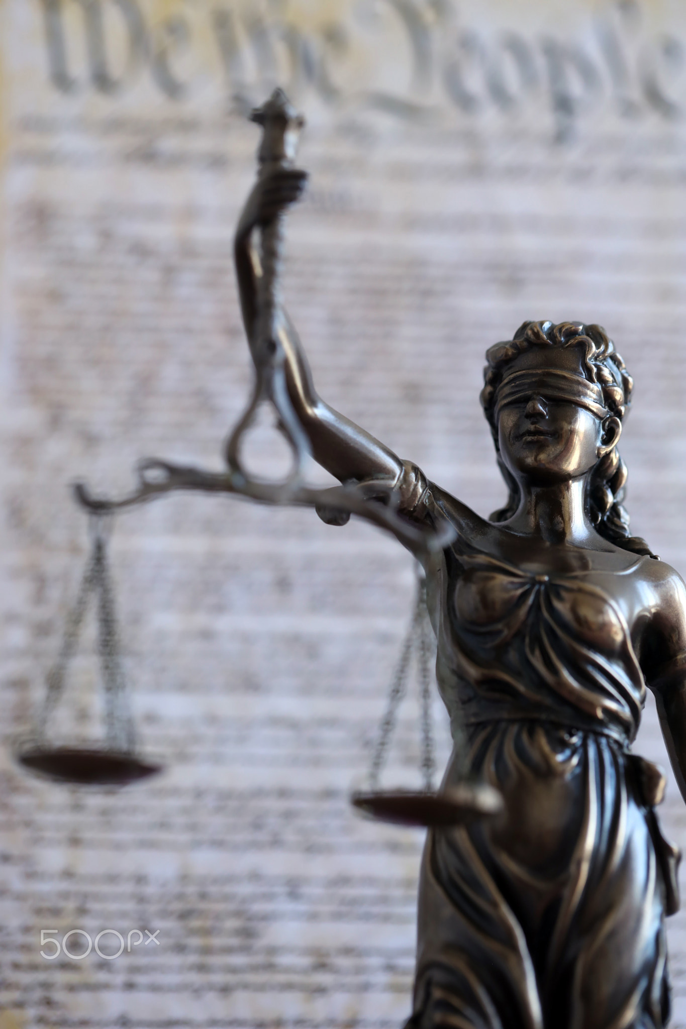 Lady Justice statue on background of US Constitution. Lawsuit and punishment in USA