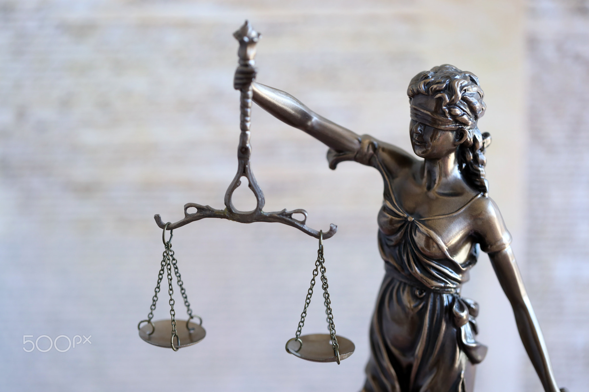 Lady Justice bronze statue and US Constitution blurred page close up. Lawsuit and punishment