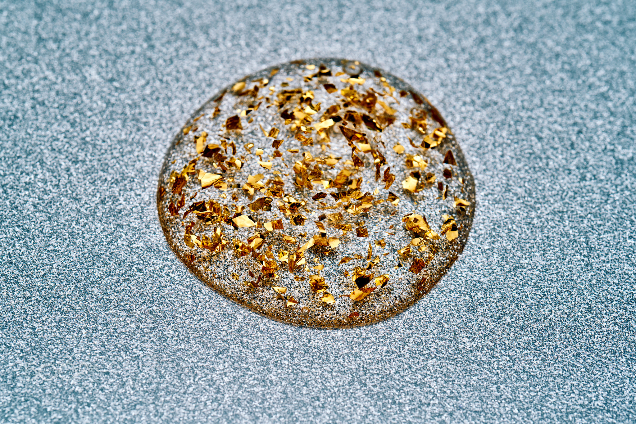 Golden glitter liquid drop on sparkling background