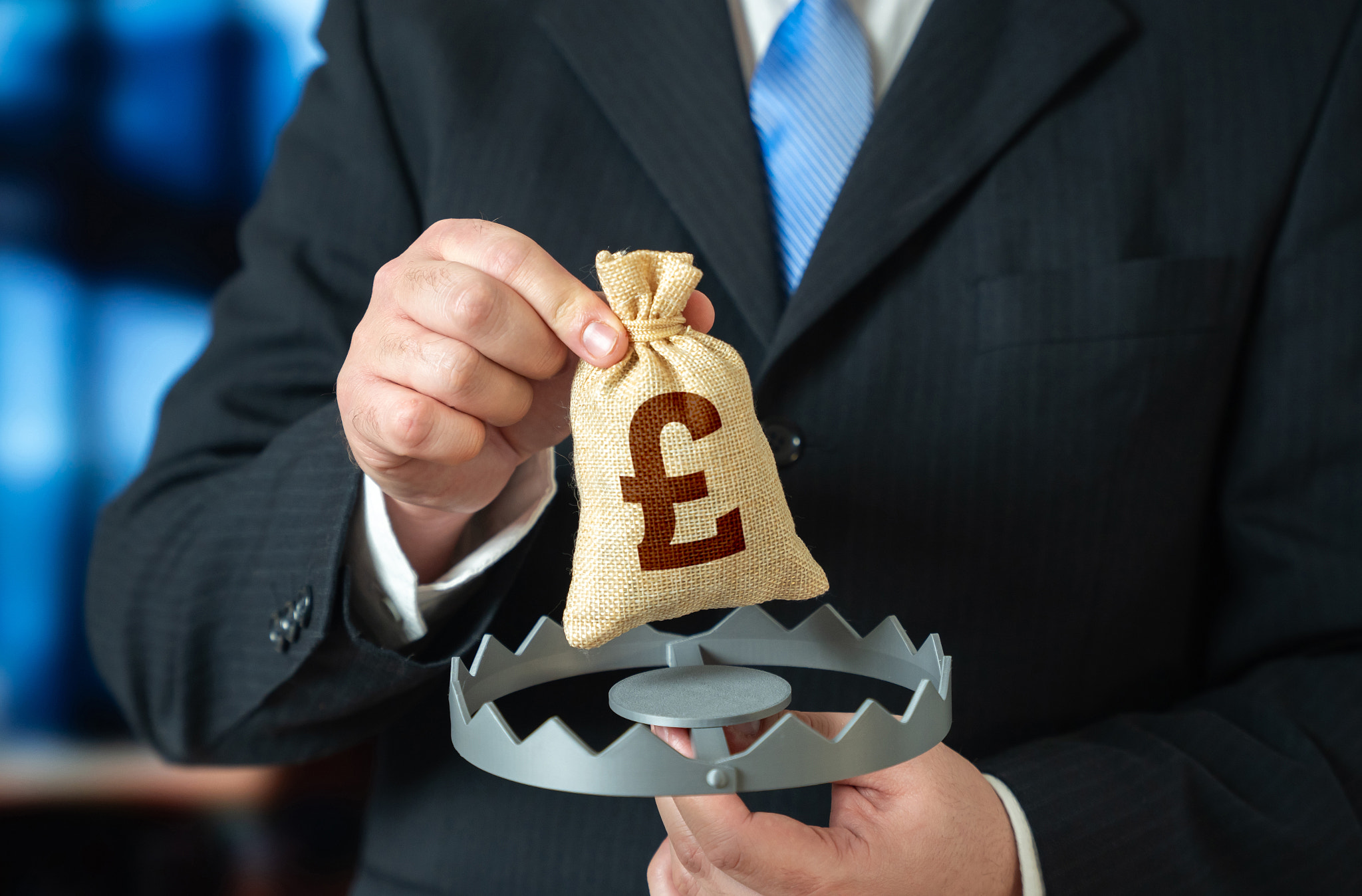 A businessman is holding the British pound in a trap. A financial trap, risk of fraud. High debts, u