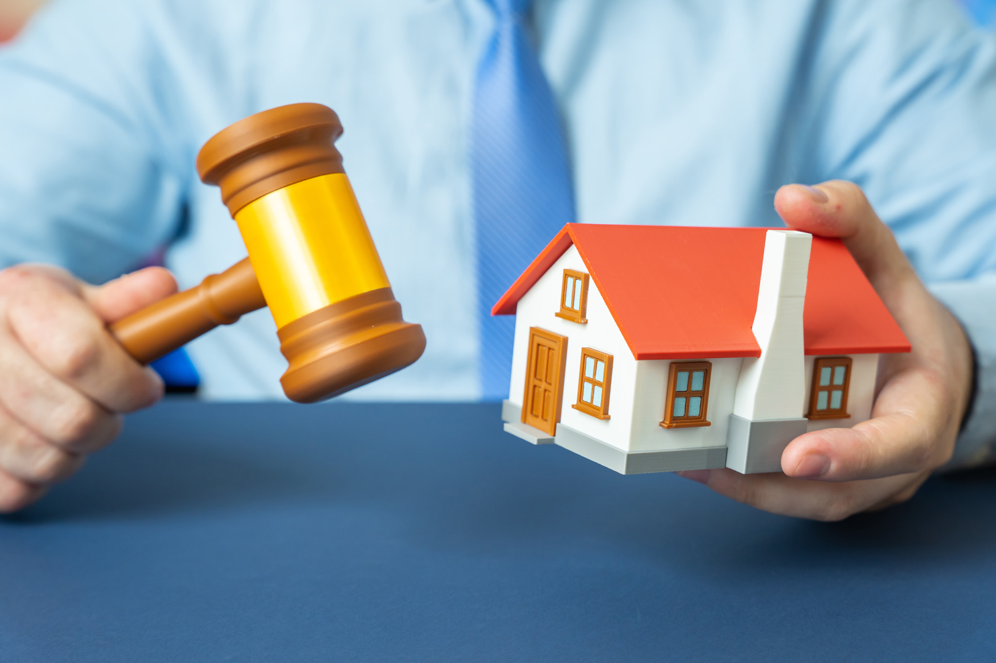A man holding a judge's gavel and a house. Property valuation and court disputes. Legal assistance a