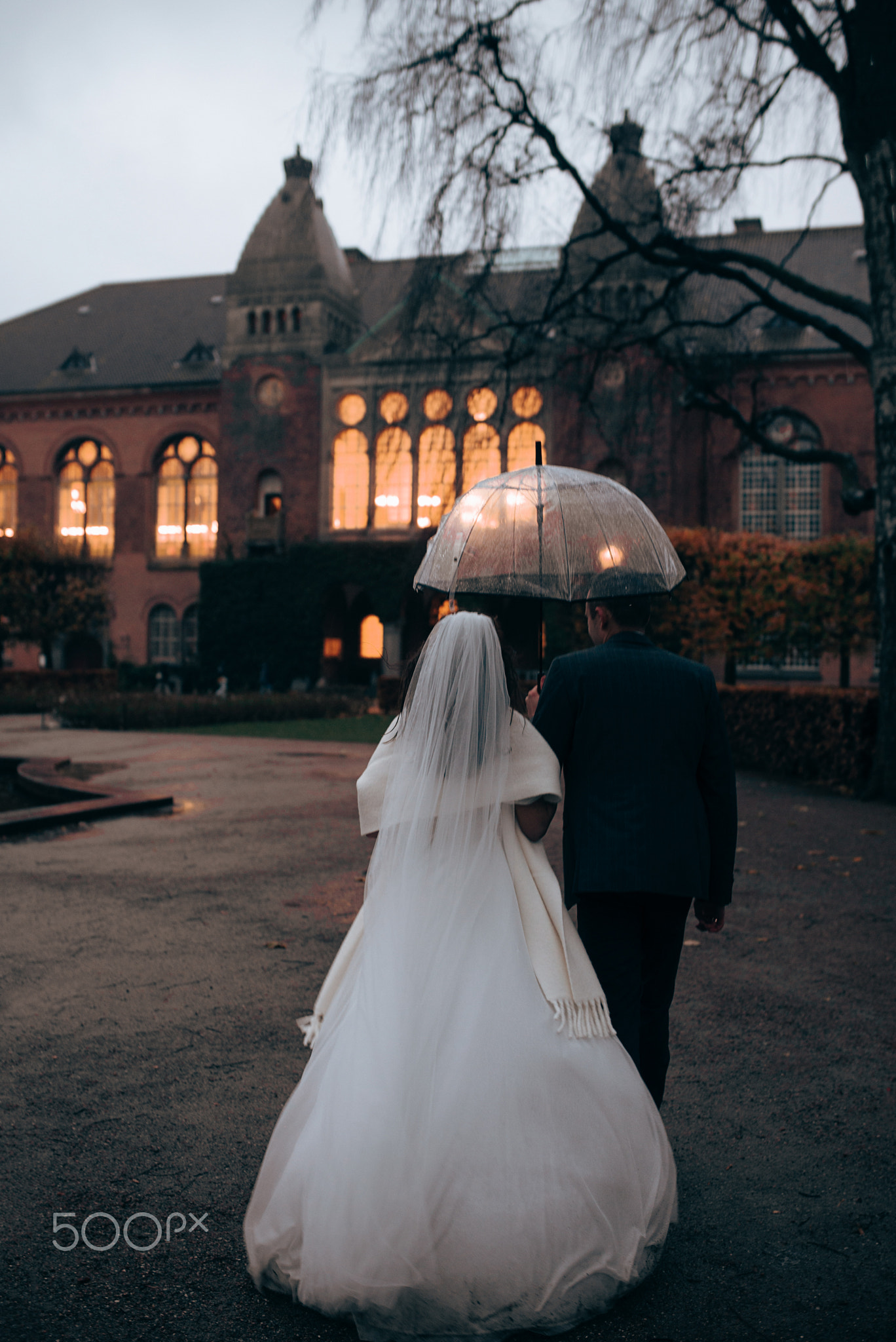 Bride and groom walking away under umbrella after wedding in Denmark