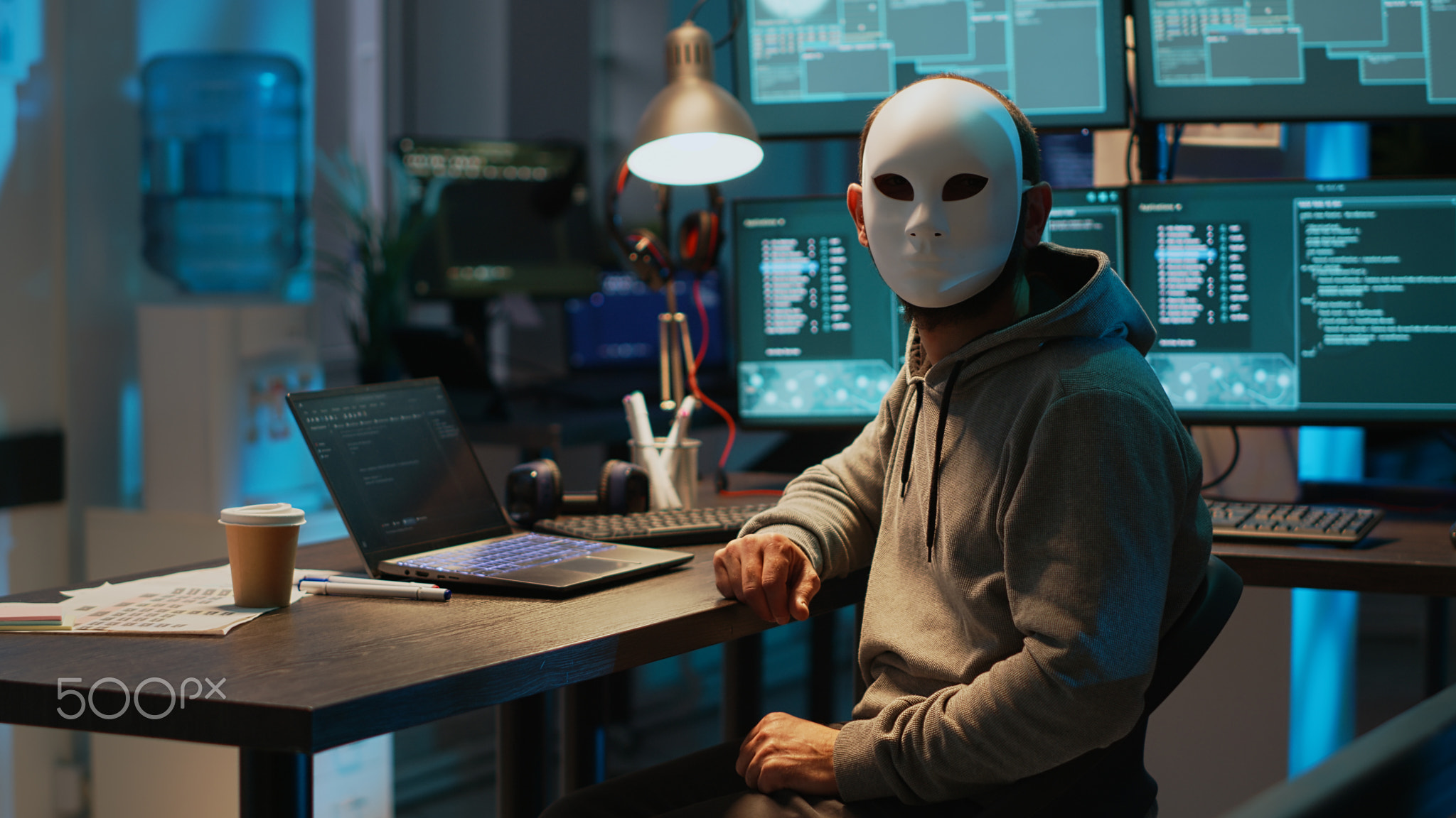 Masked scammer hacking computer network late at night