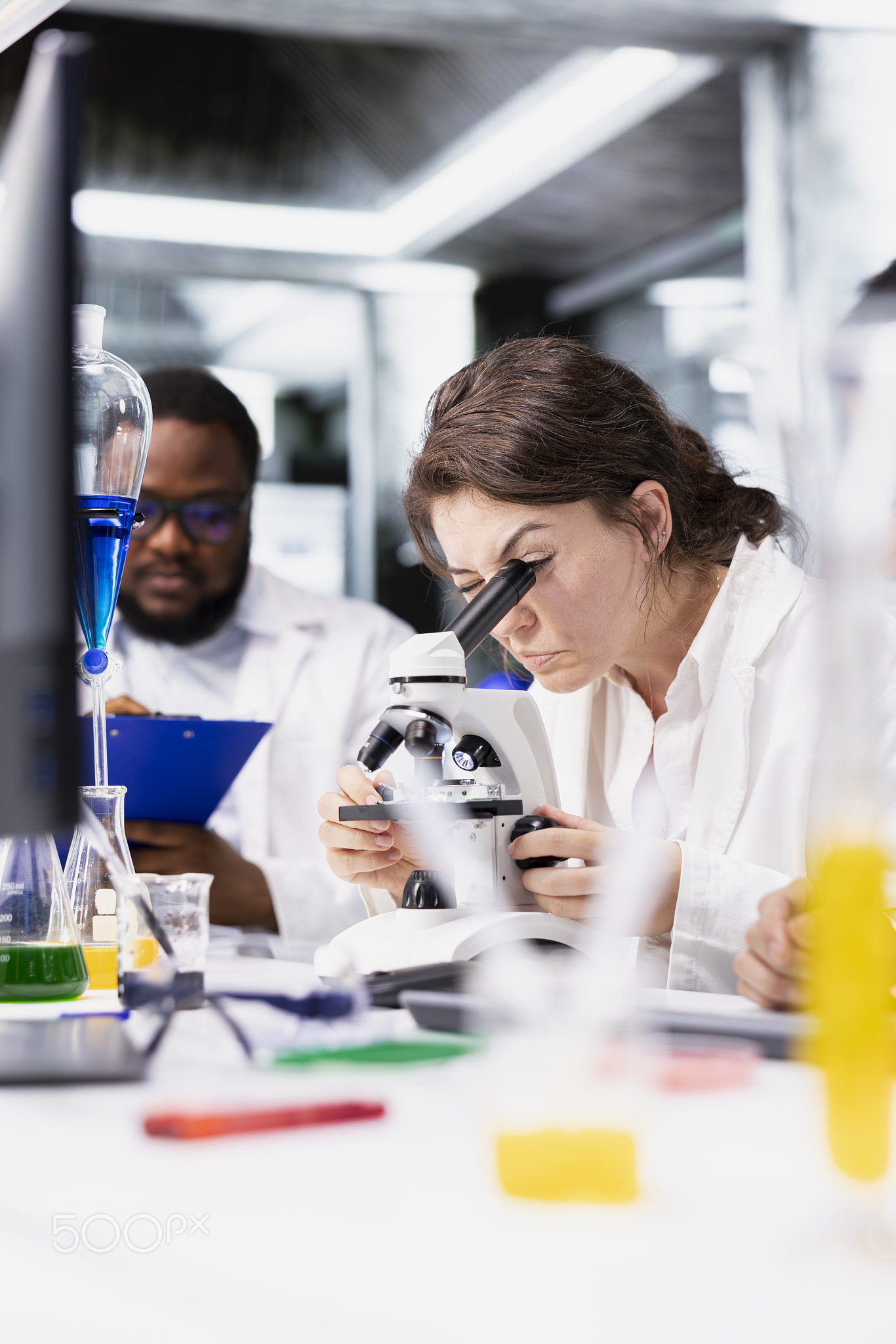 Team of microscopists working together in controlled laboratory environment
