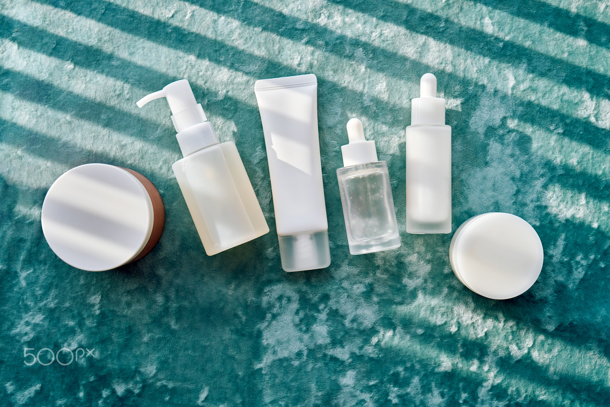 Cosmetic containers and skincare products on velvet background