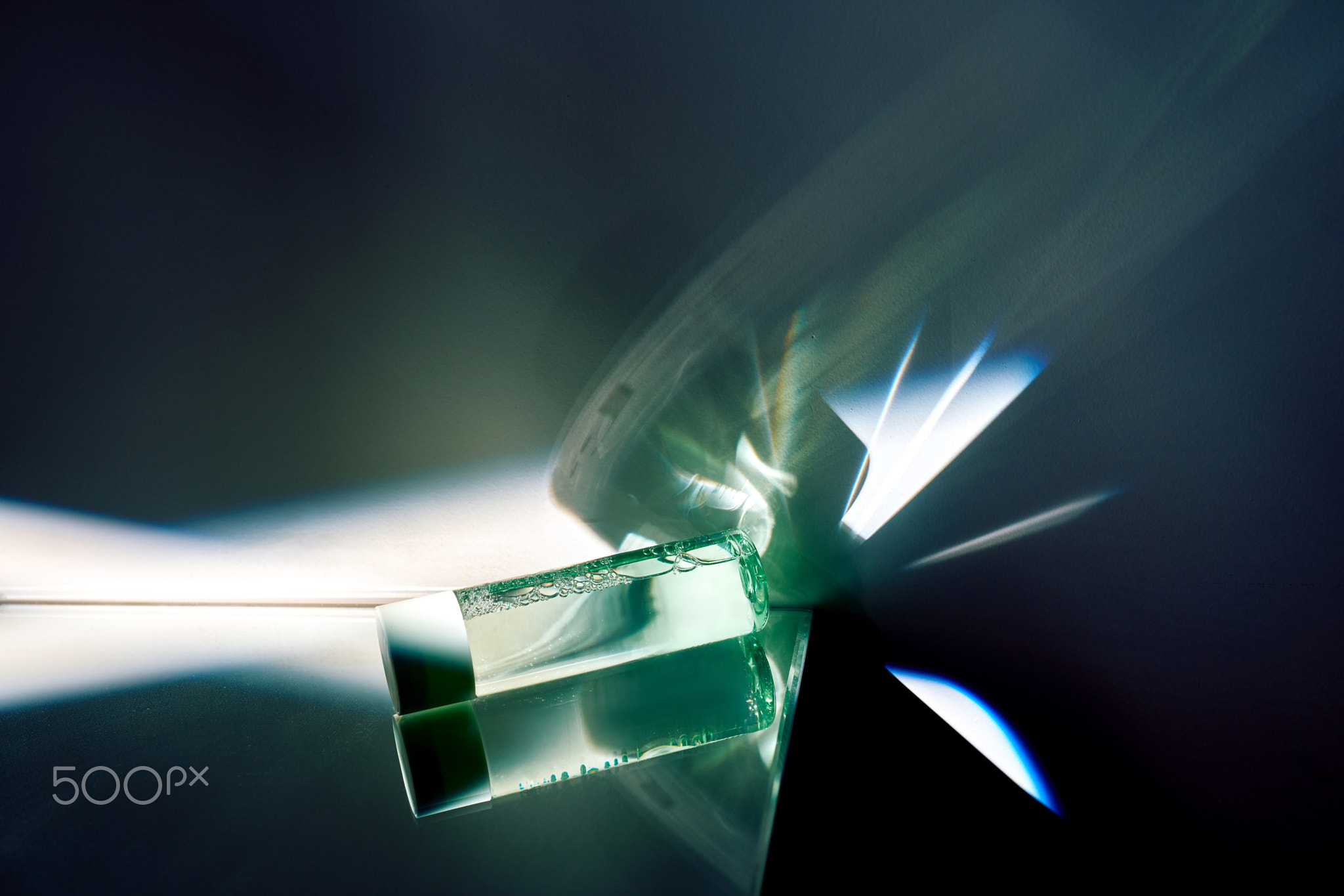 Cosmetic serum vial creating abstract light reflections